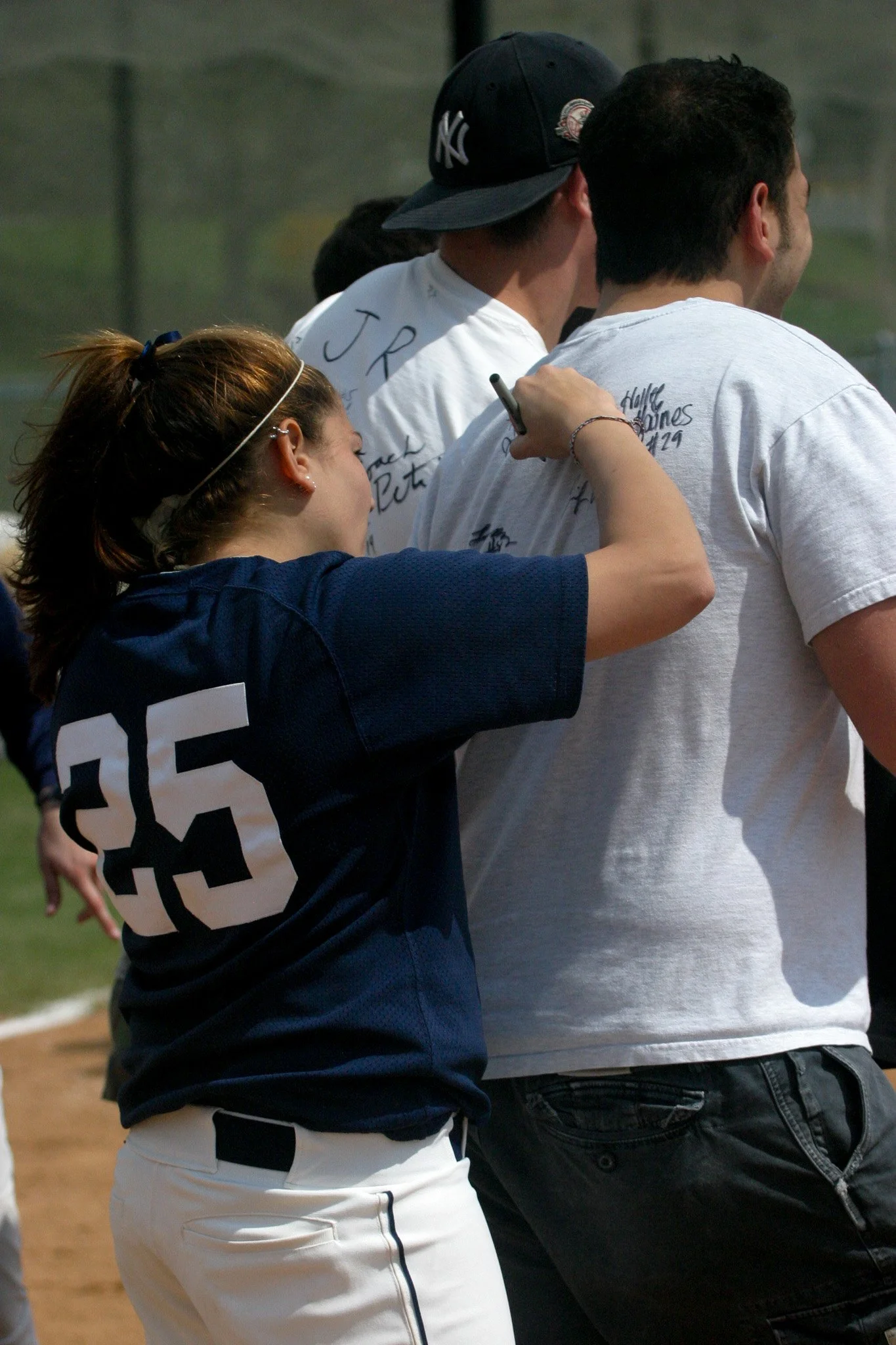 A woman signing autographs on the back of people at a sports event.