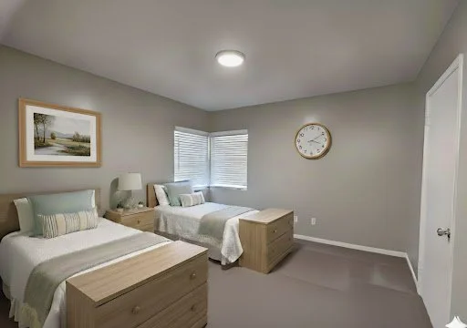A bedroom with two single beds, wooden nightstands, a lamp, a framed picture on the wall, a window with blinds, a large round wall clock, and a closed door.