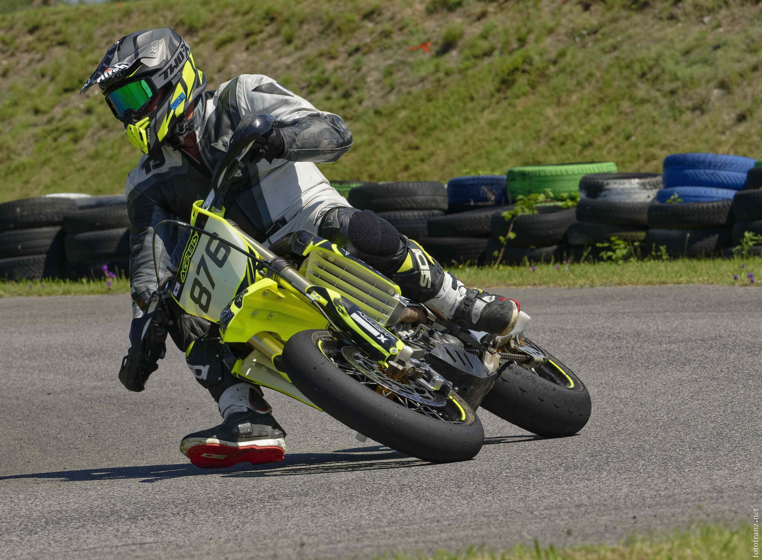 Motorradfahrer in Schutzkleidung fährt auf einer Rennstrecke, um das Knie auf dem Boden zu stabilisieren.