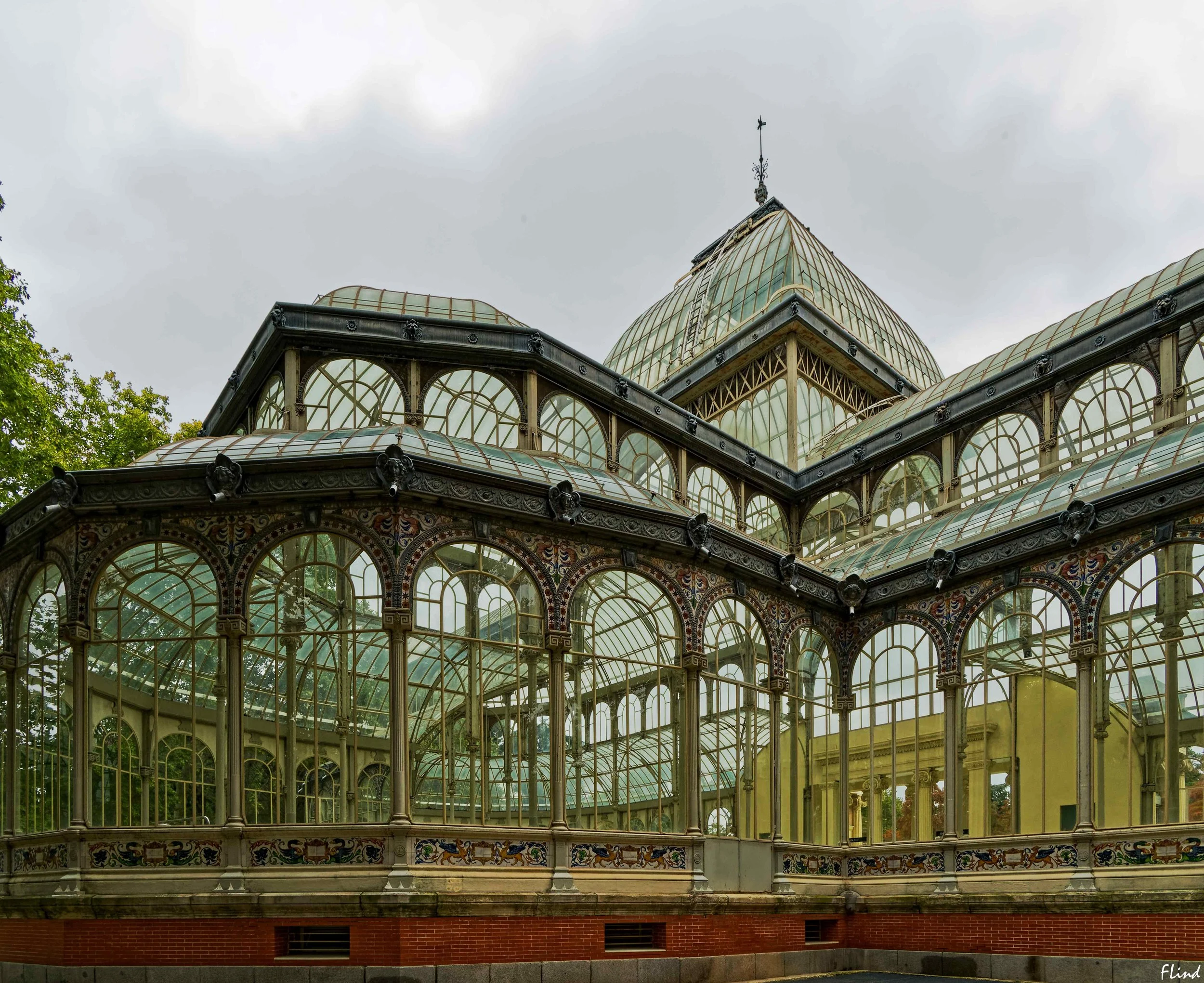 Ein elegantes viktorianisches Wintergarten mit viel Glas und Metallrahmen, verziert mit bunten Fliesen am unteren Rand