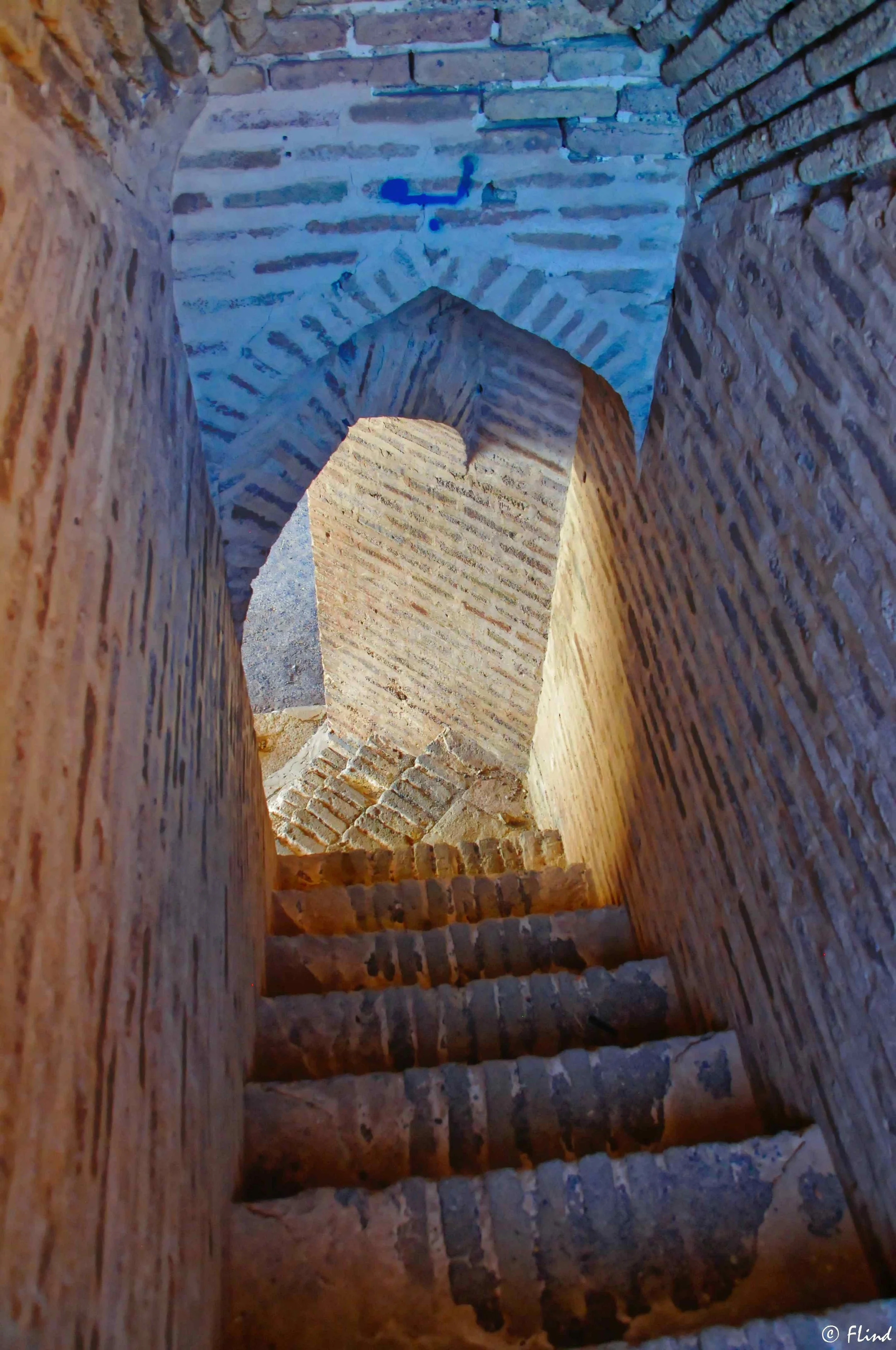 Innenaufnahme eines alten Steinturms mit einer engen spiraligen Treppe, Steinarbeiten und einem Kreuz an der Decke