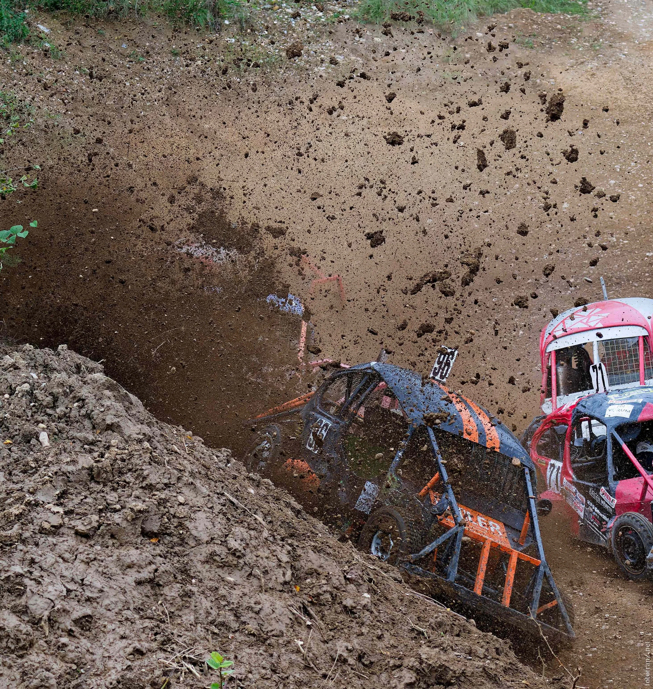 Unfall mit vier Rallye-Autos, die in einem steilen, schlammigen Hang gegeneinander prallen, Staub und Erde fliegen, in einer Offroad-Rennveranstaltung.