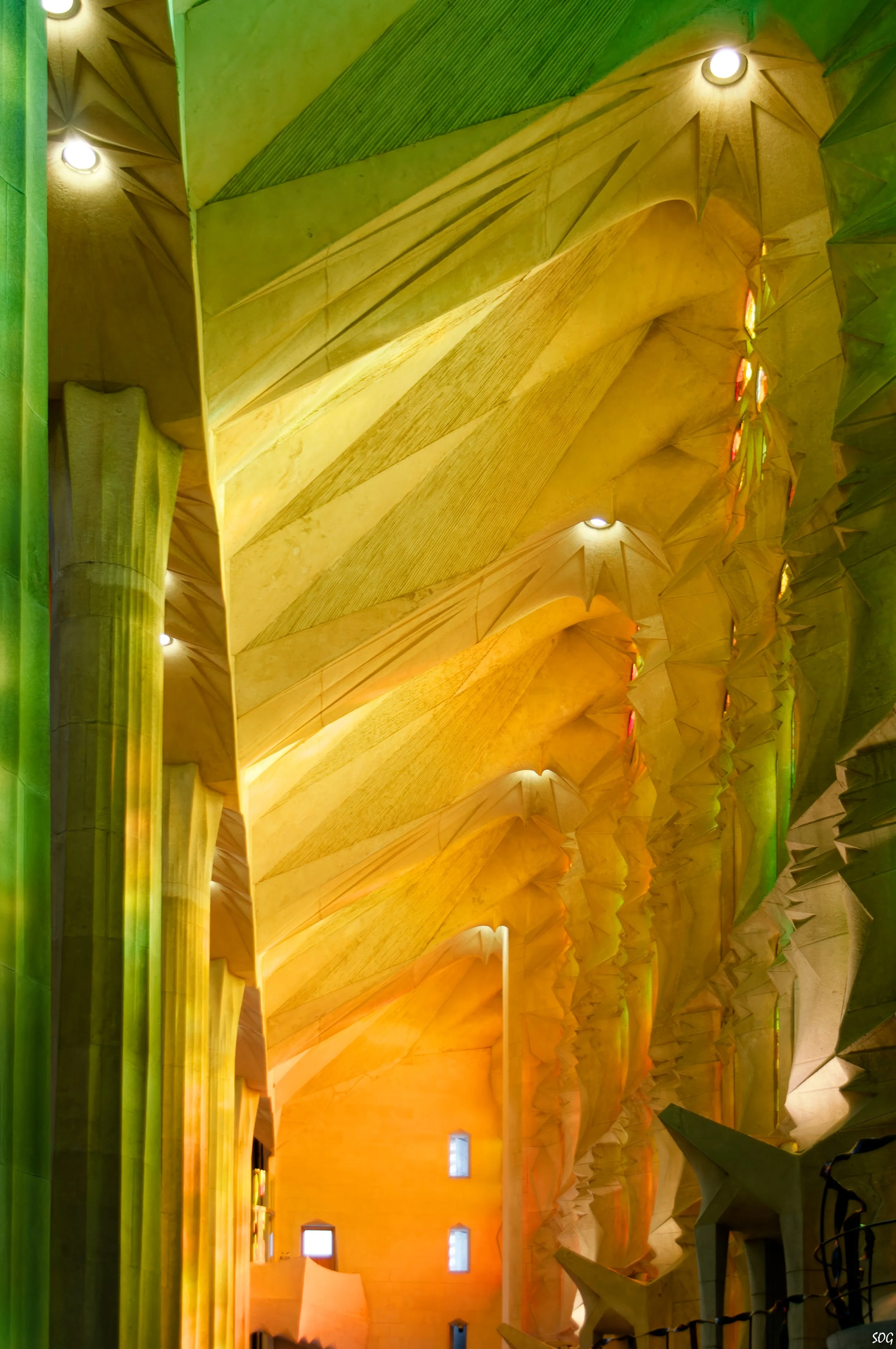 Innenansicht der Sagrada Família mit farblich beleuchteten Säulen und gewölbtem Deckenboden.