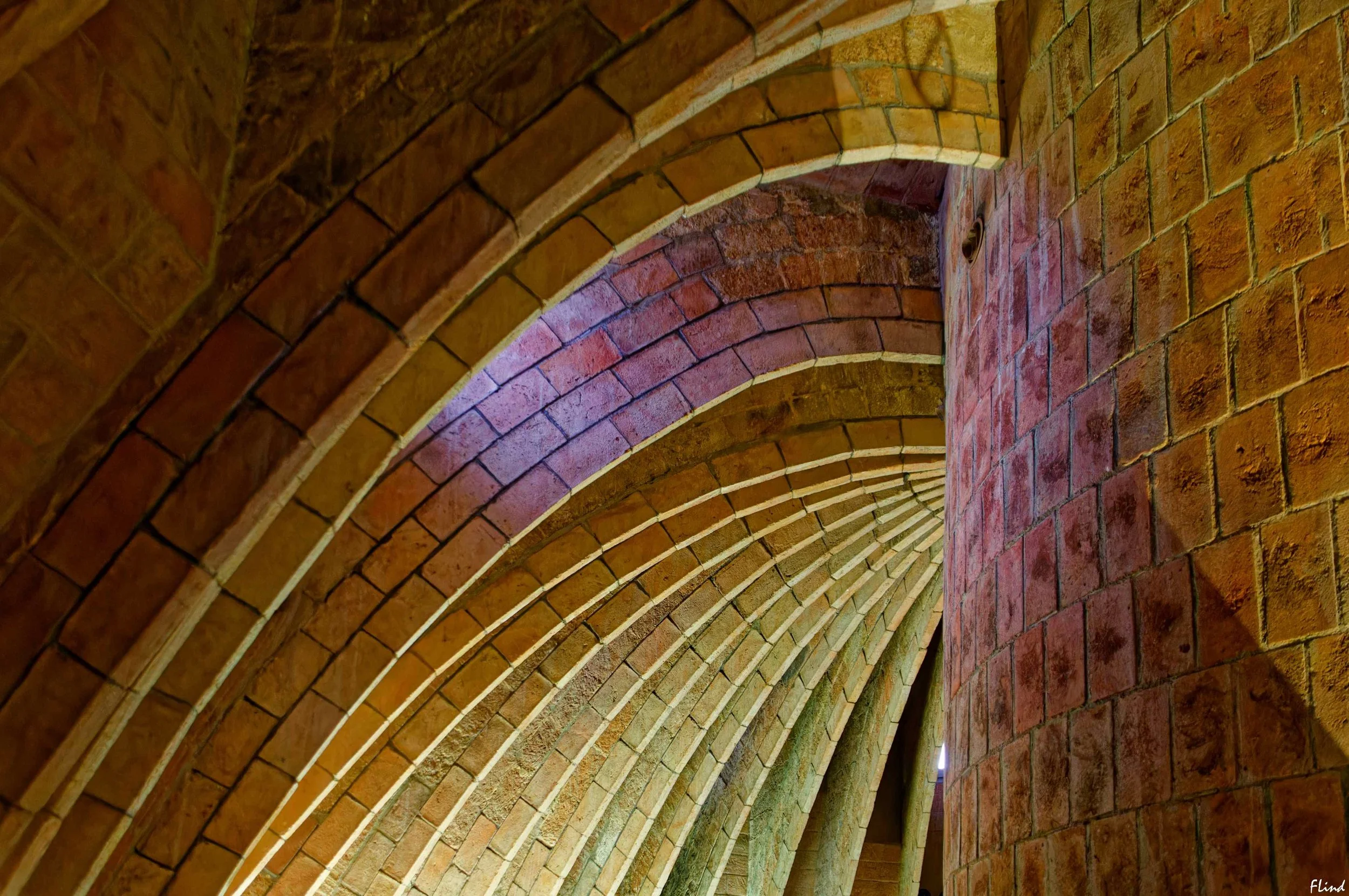 Blick in einen gewölbten, gemauerten Tunnel mit roten Ziegelsteinen, die eine schmale Spitze bilden.