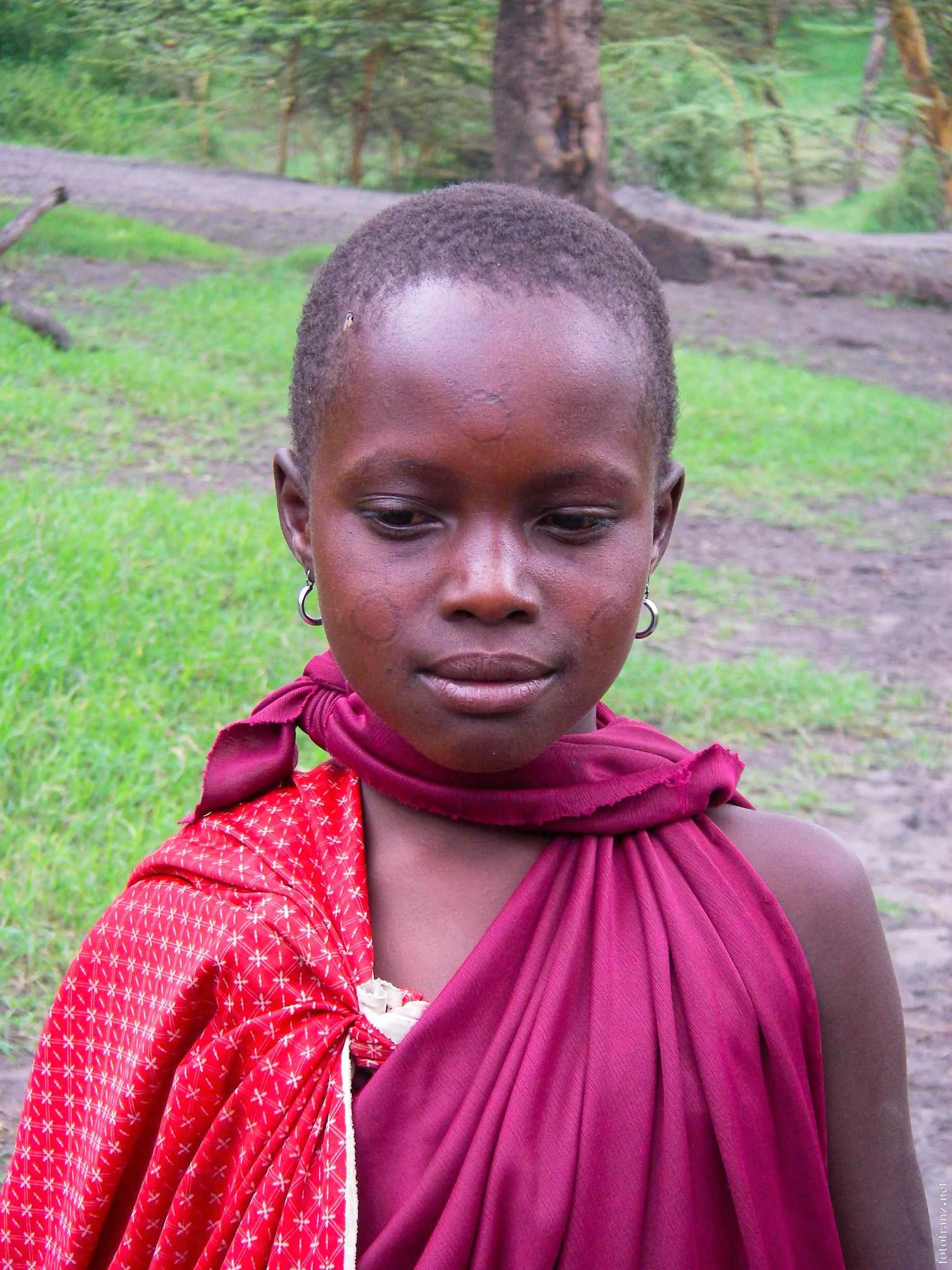 Junge mit roten Kleidungsstücken im grünen Waldumfeld