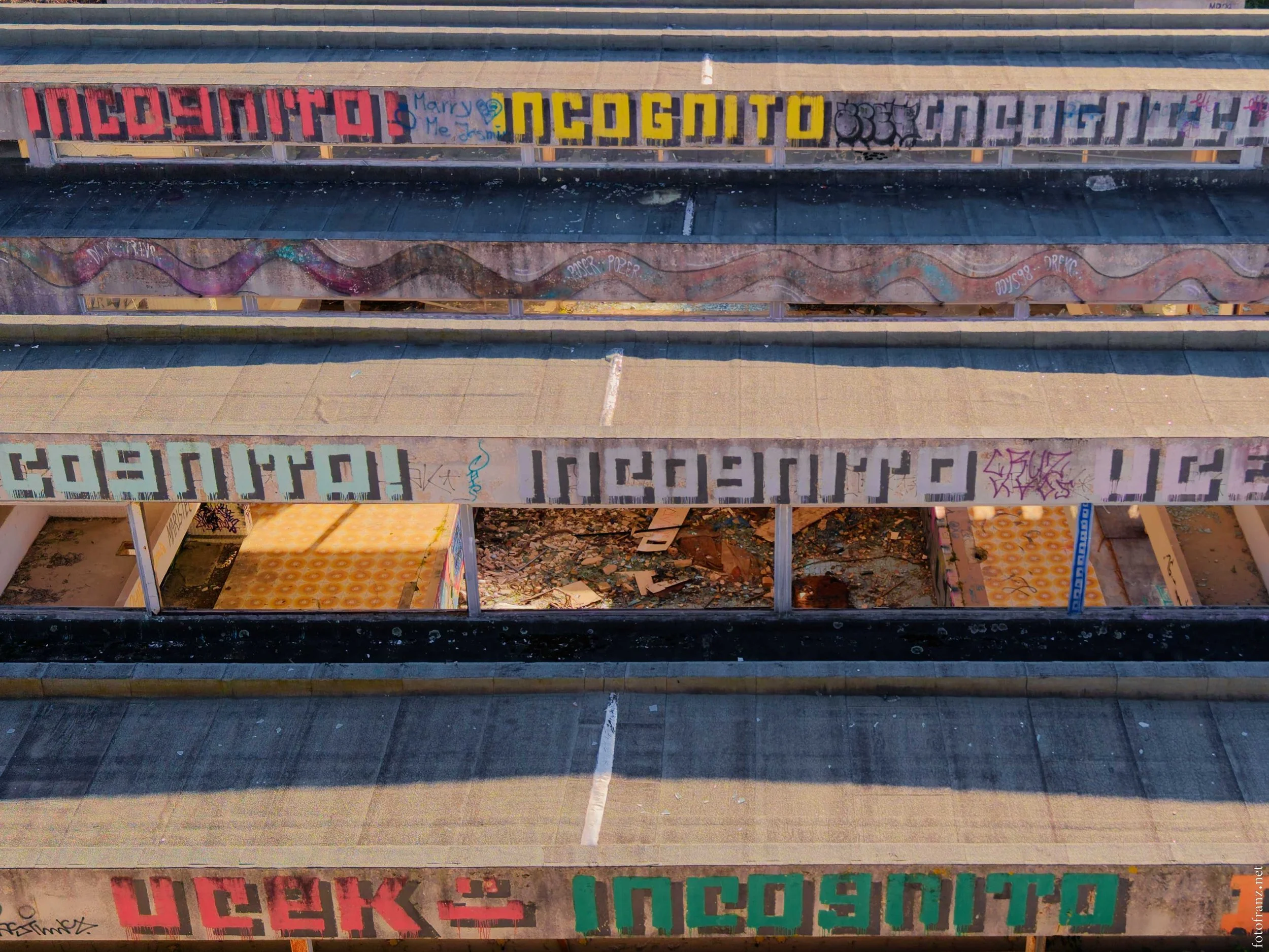 Mehrstöckiges Parkhaus mit Graffiti und leeren, verfallenden Parkdecks, einige Bereiche sind offen und mit Müll bedeckt.