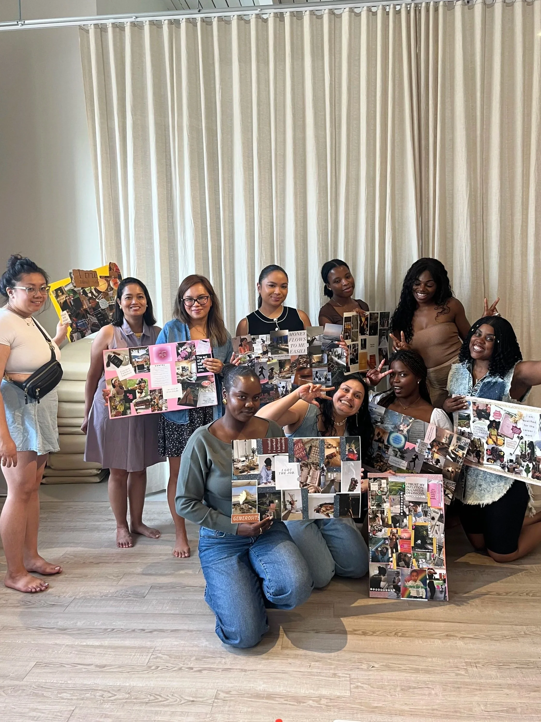 group of women of colour holding colorful poster board displays, some making peace signs indoors.