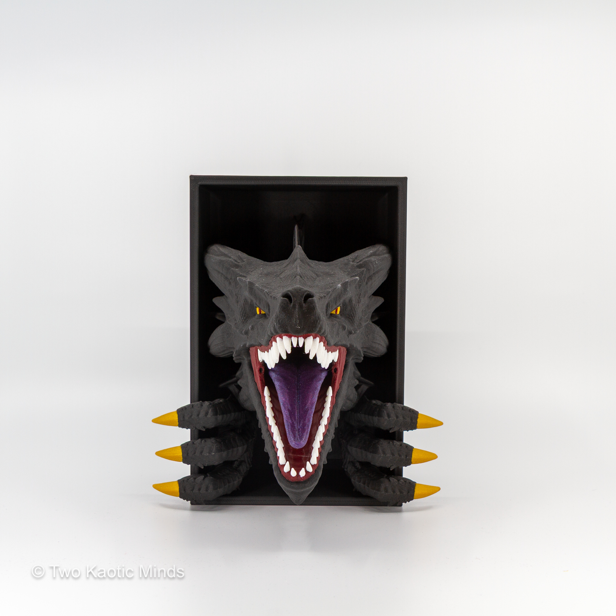 3D printed Emerging Dragon book nook in multi-color black, gold, and purple PLA, roaring dragon head with open jaws and gold claws bursting from a matte black box, front view