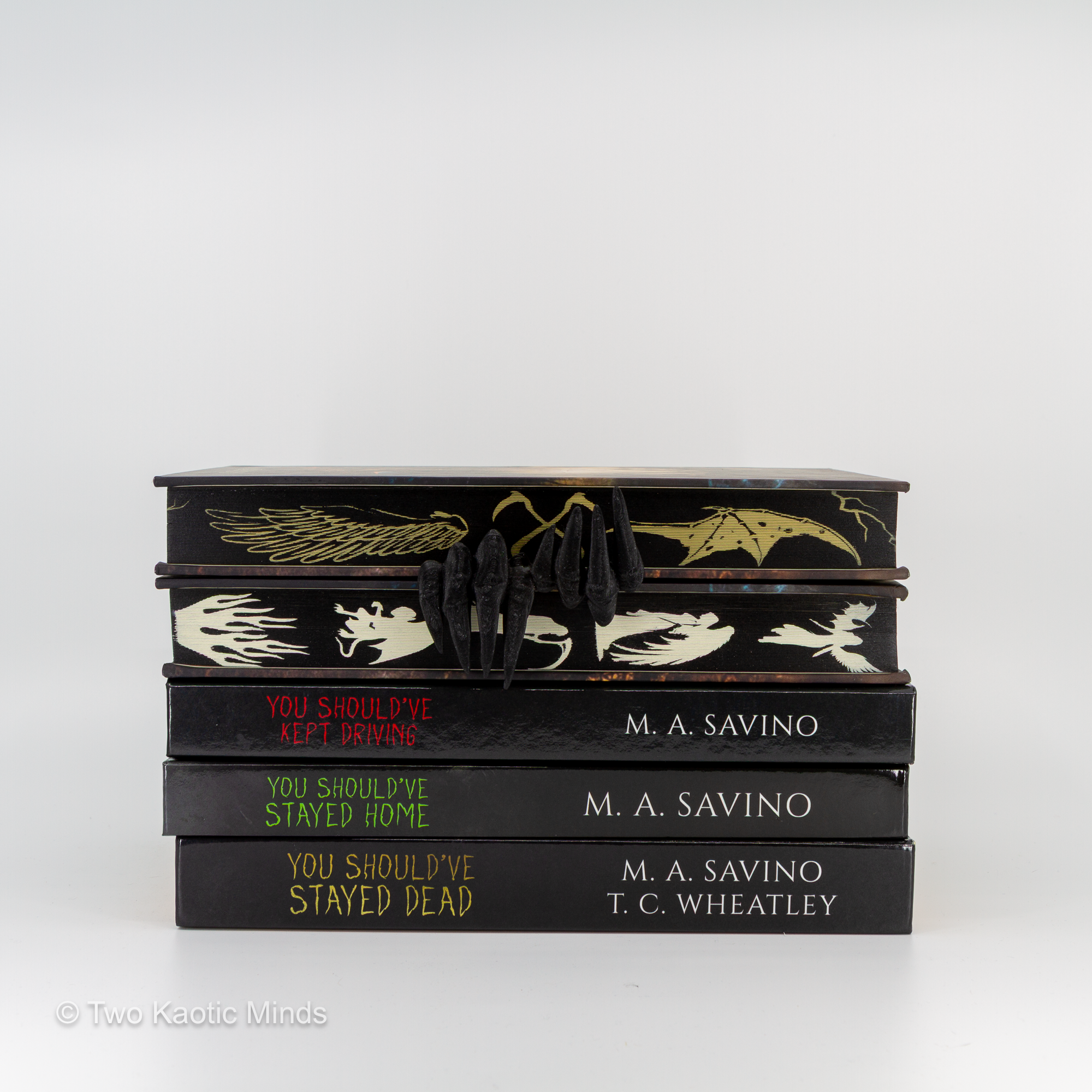 Demon Hands bookmark shown with a stack of books, matte black demon claw bookmark visible on the top book