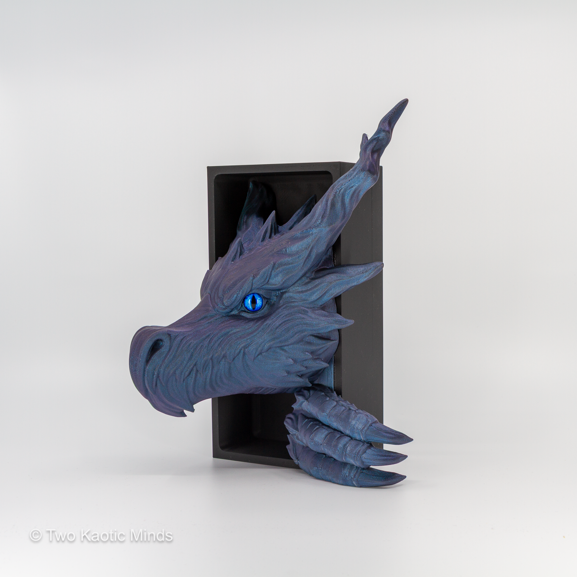 3D printed Shadow Dragon book nook in iridescent Starlight Twilight blue-purple PLA with blue glass eyes, dragon head emerging from matte black box, front angle view