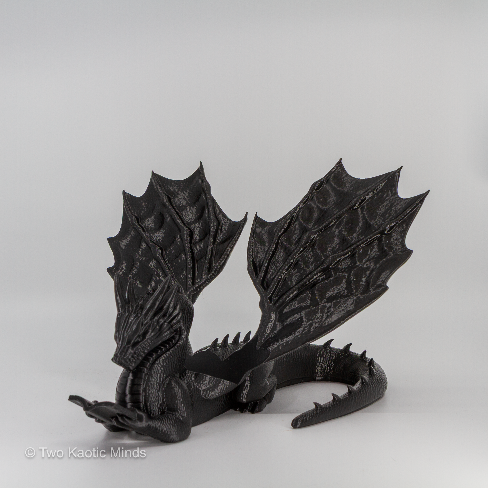 Rear angle view of black 3D printed dragon book holder showing full wing span and textured detail