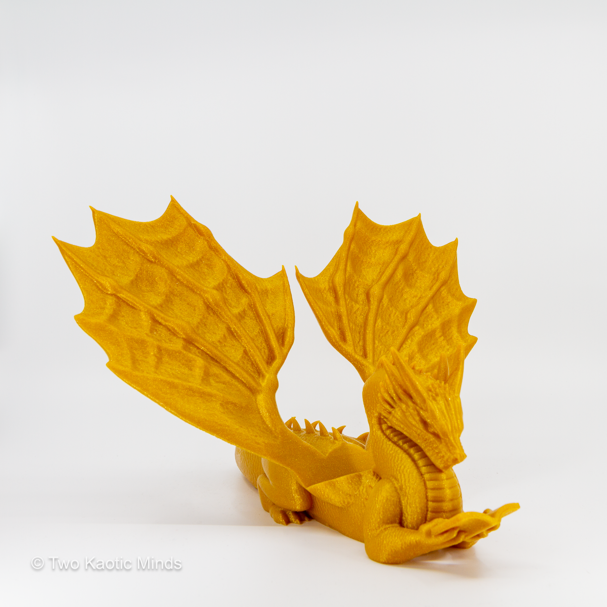 3D printed gold dragon book holder front view with wings spread wide on grey background