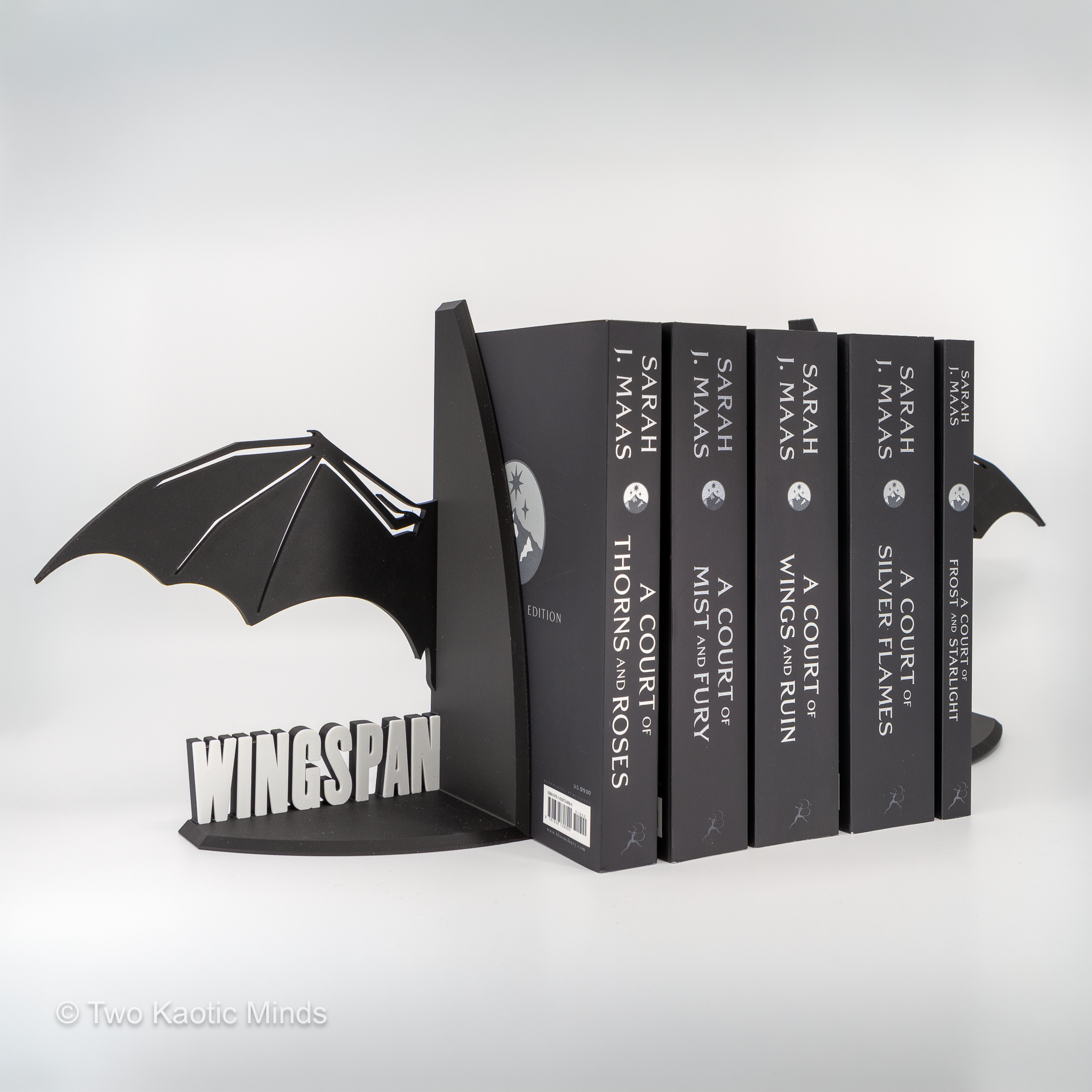 Wingspan Matters bookends holding fantasy books, angled view from the WINGSPAN side showing full wing spread and book collection