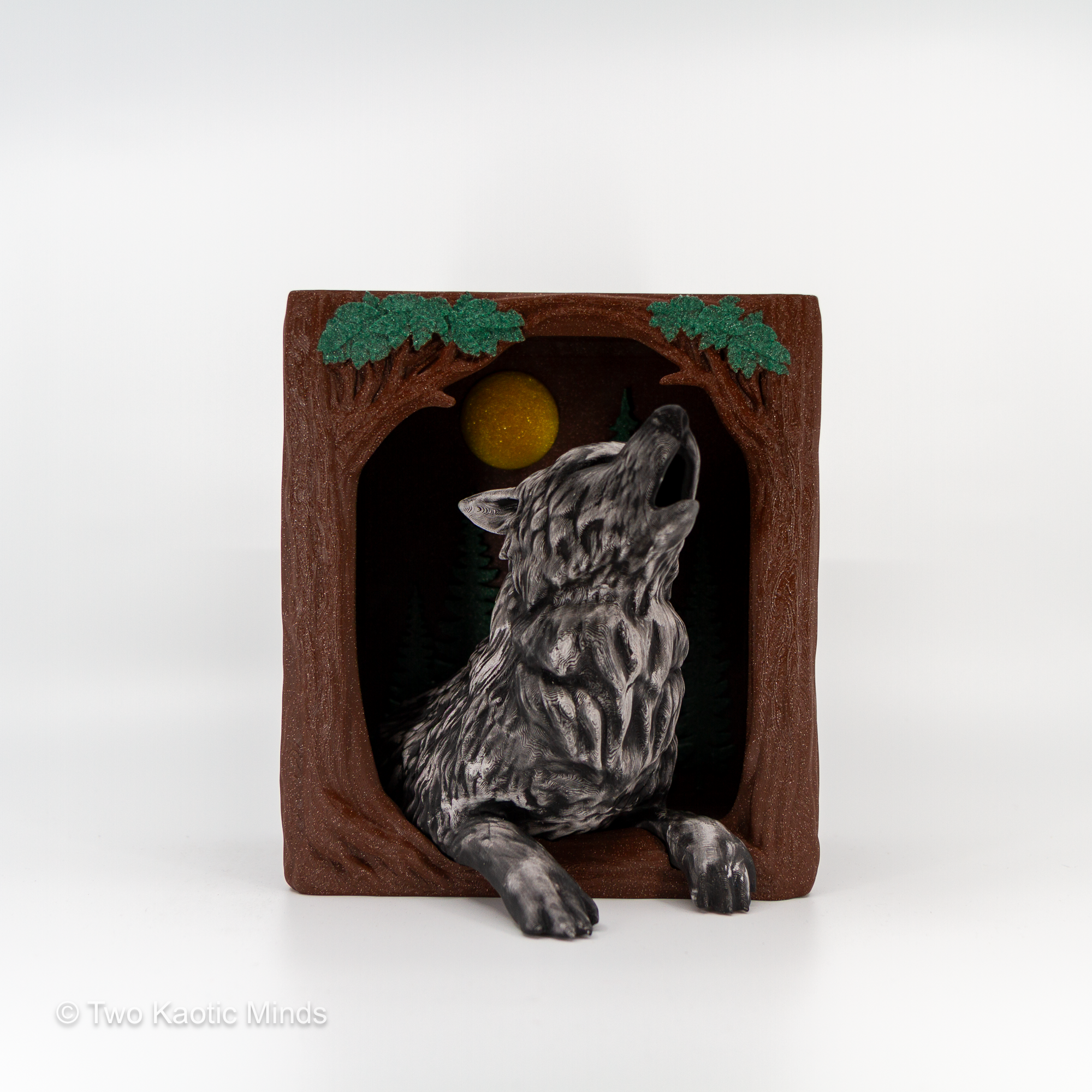 3D printed Howling Wolf book nook with silver Rub and Buff wolf howling at a gold moon inside a brown hollow log with green foliage, front view