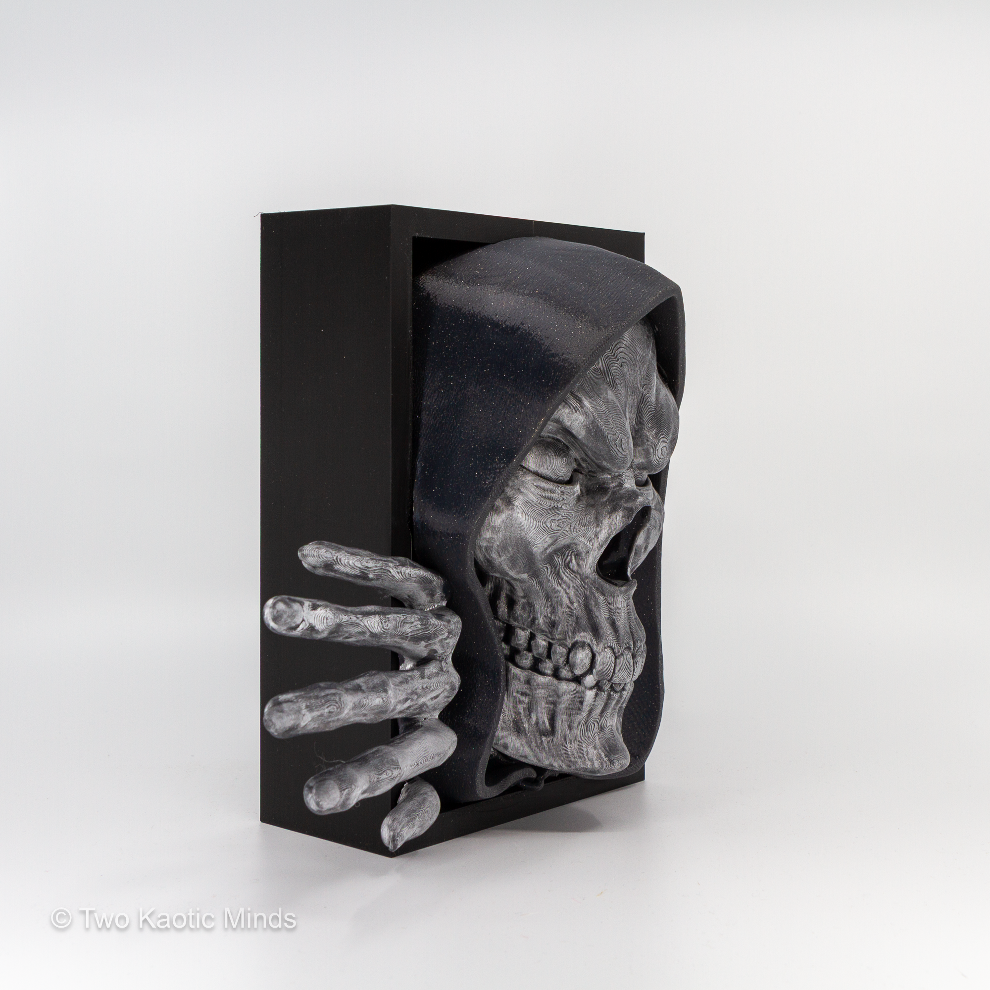 Side view of the Bone Keeper book nook showing the depth of the matte black outer box and skull profile with clawed hand detail
