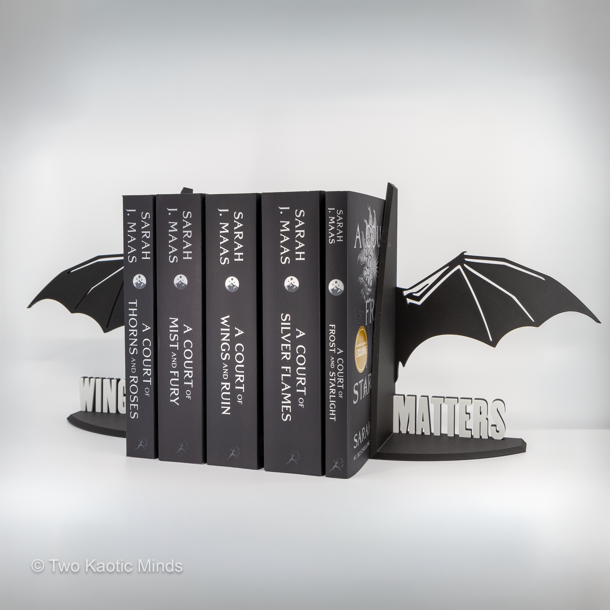 Wide angled view of both Wingspan Matters dragon wing bookends holding a full row of fantasy books from behind