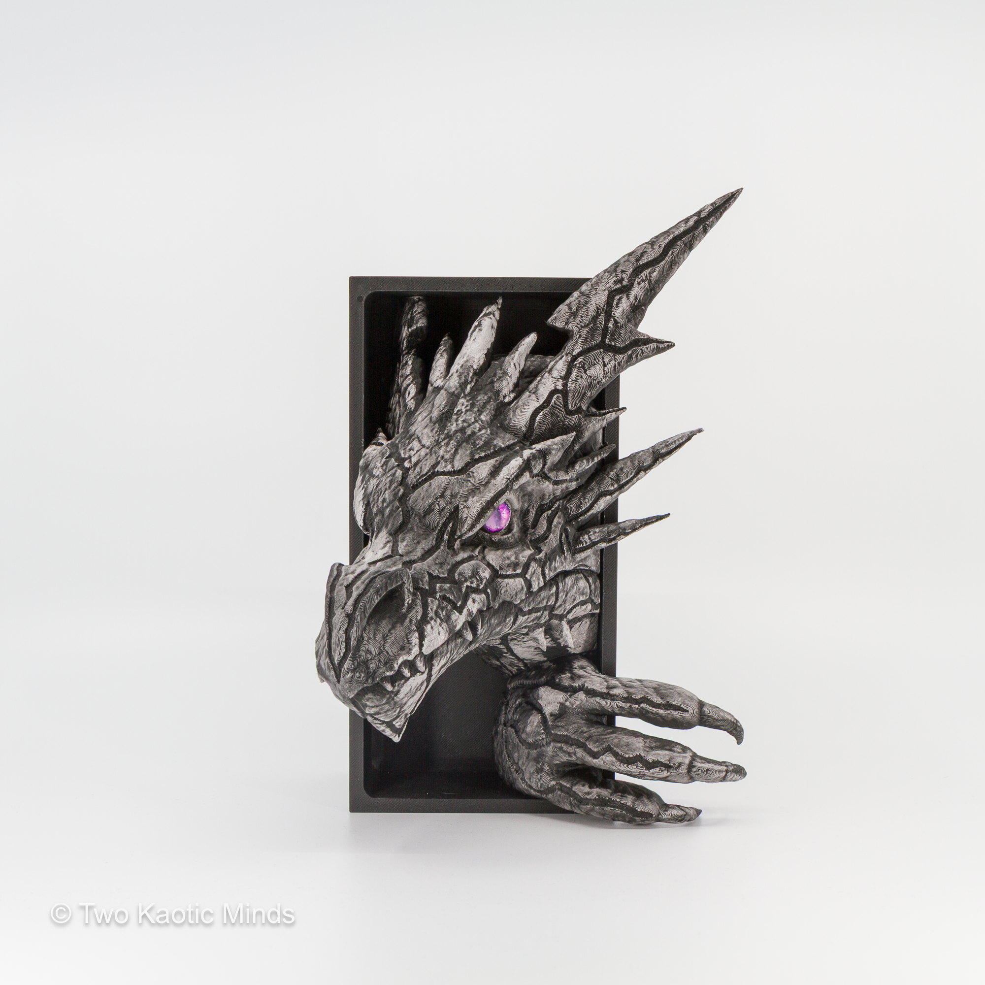 Angled front view of the Lightning Dragon book nook showing heavily armored pewter-finished scales, razor-sharp spines, and vivid purple glass eye detail