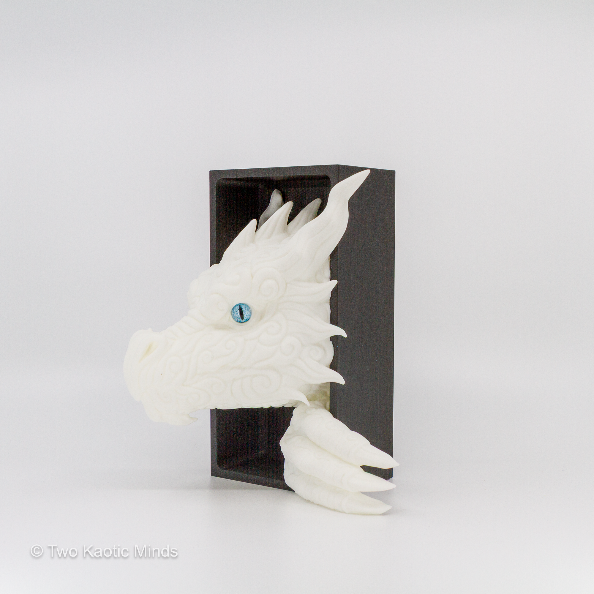 3D printed white Cloud Dragon book nook showing detailed dragon head with blue eyes emerging from a matte black box, front angle view on grey background