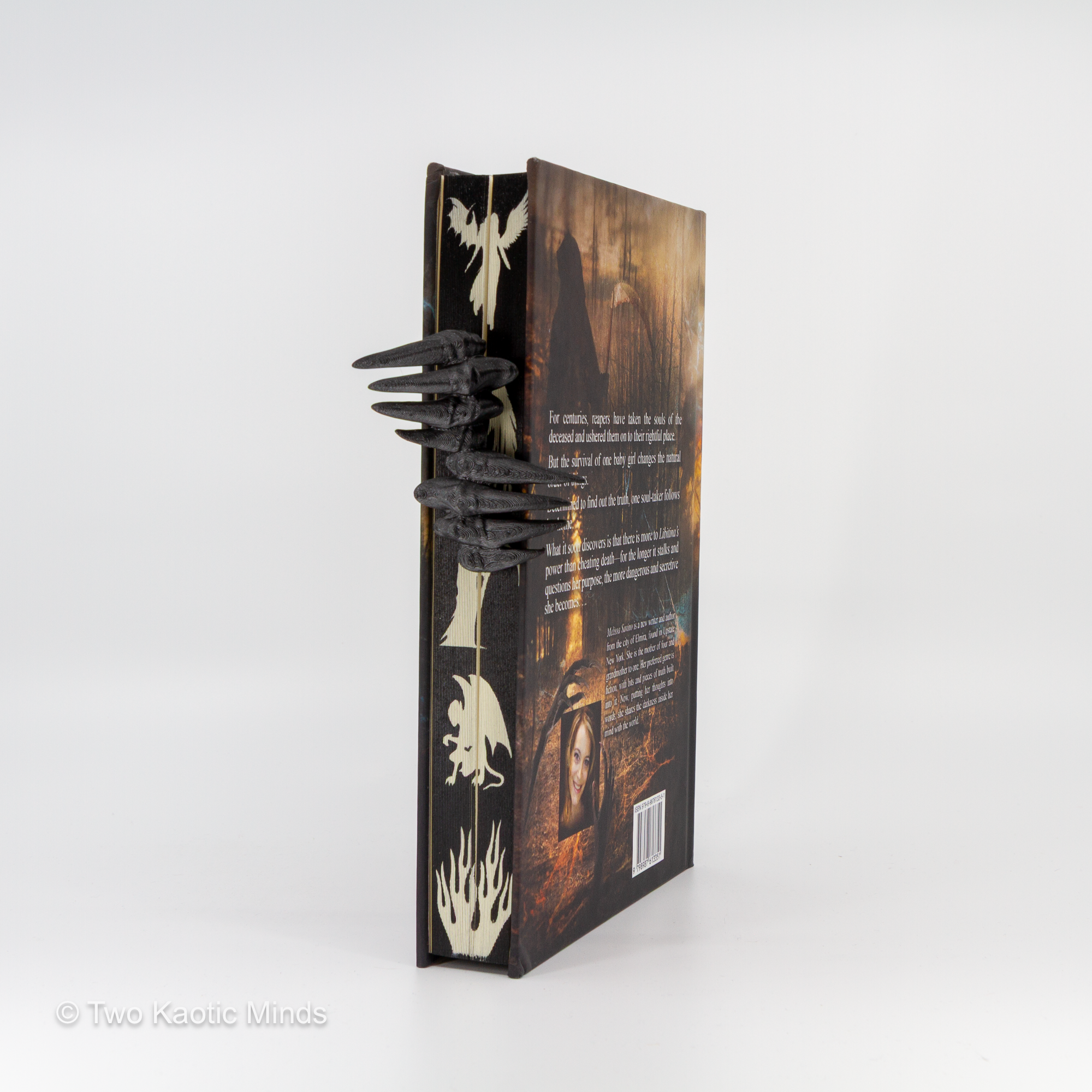 Side view of the Demon Hands bookmark on a book showing the depth of the claw grip