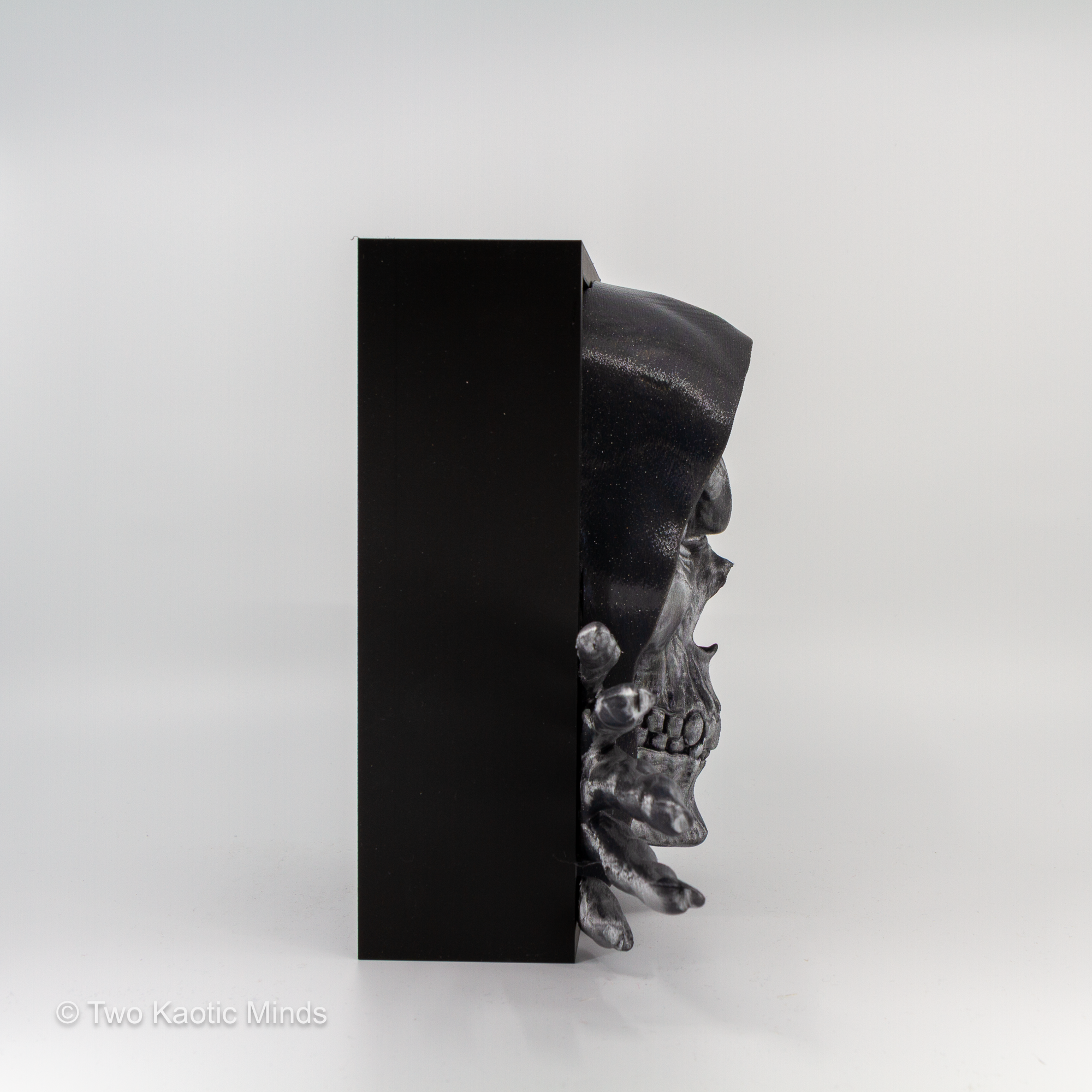 Rear angle view of the Bone Keeper book nook showing the matte black outer box structure and skull emerging from the side