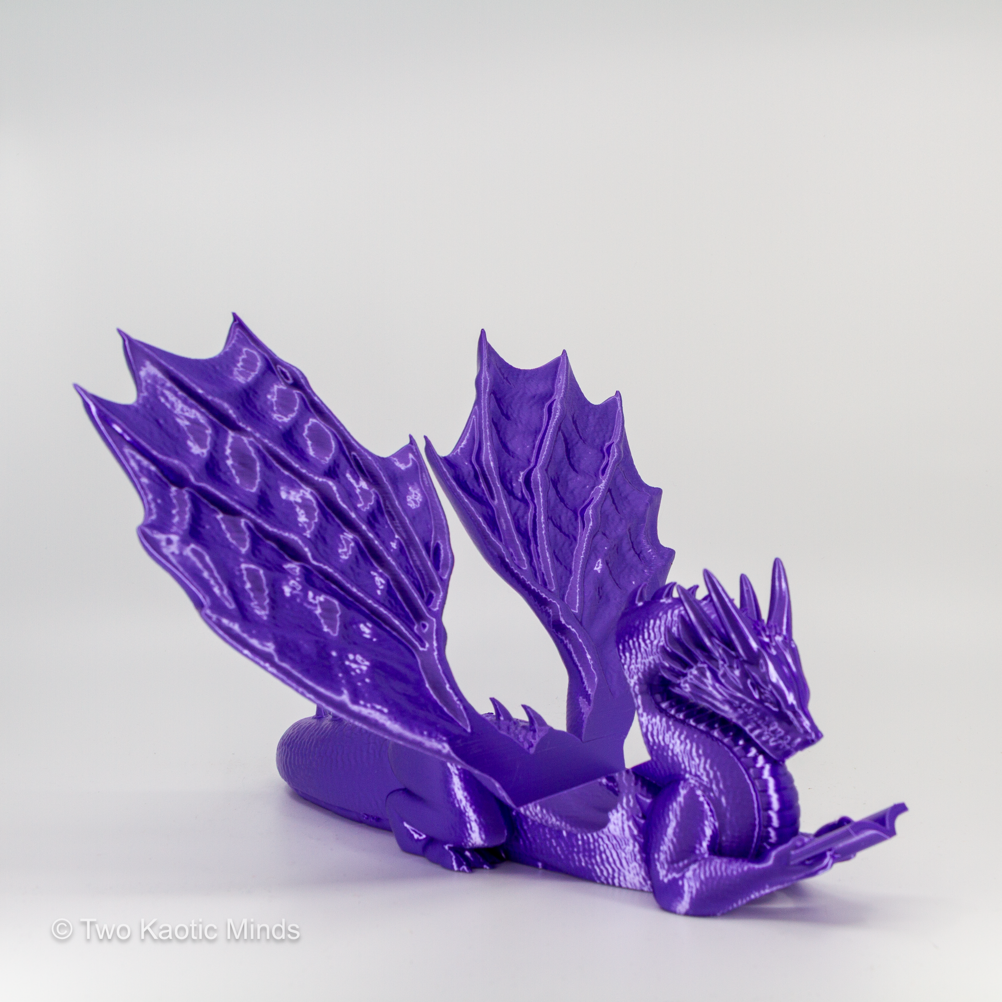 3D printed purple dragon book holder front view with wings spread on grey background