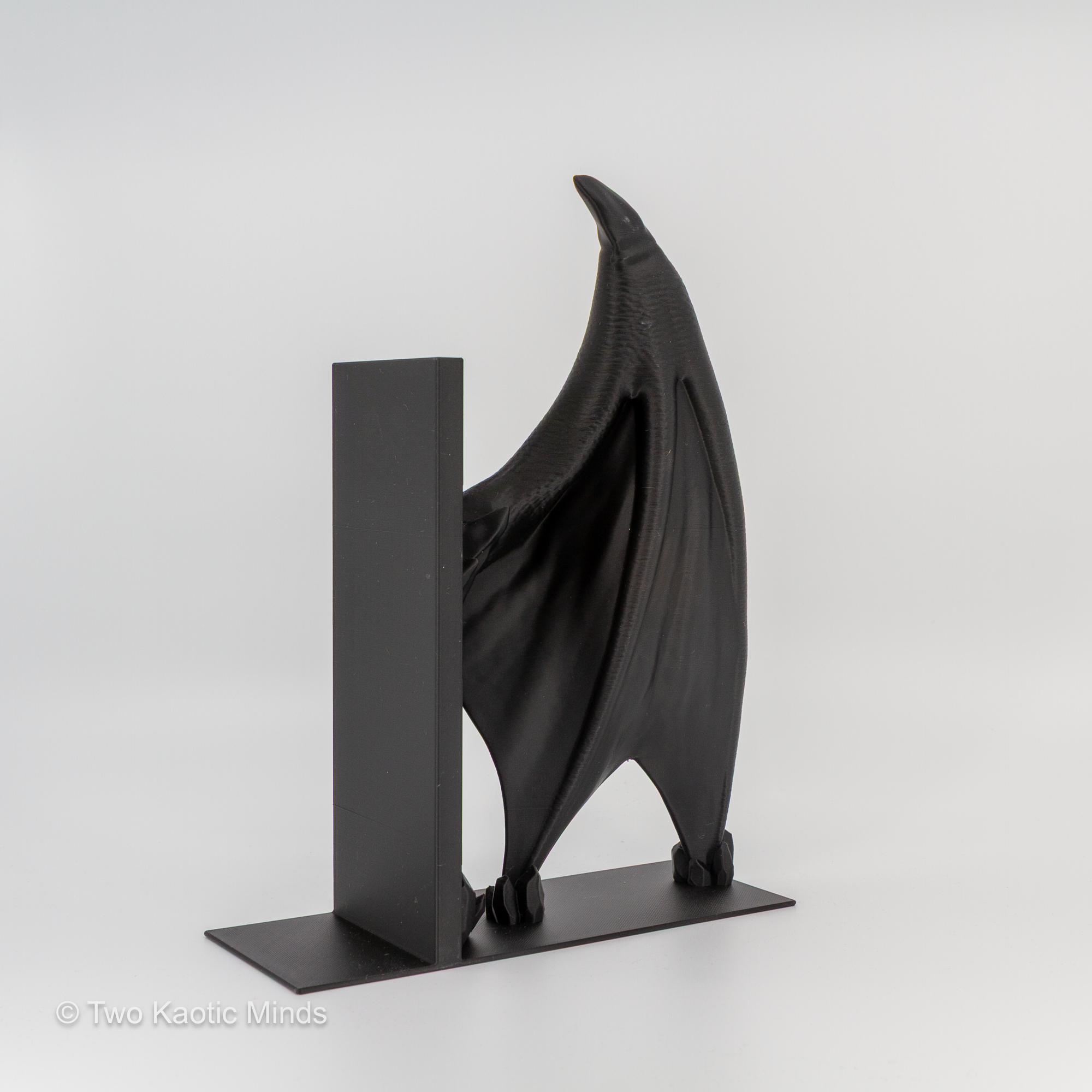 Single matte black Frost Dragon wing bookend, opposite side angle showing wing texture and standing base