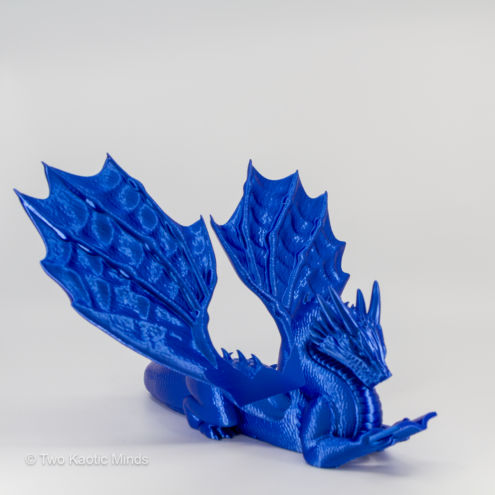 3D printed blue dragon book holder front view with wings spread on grey background