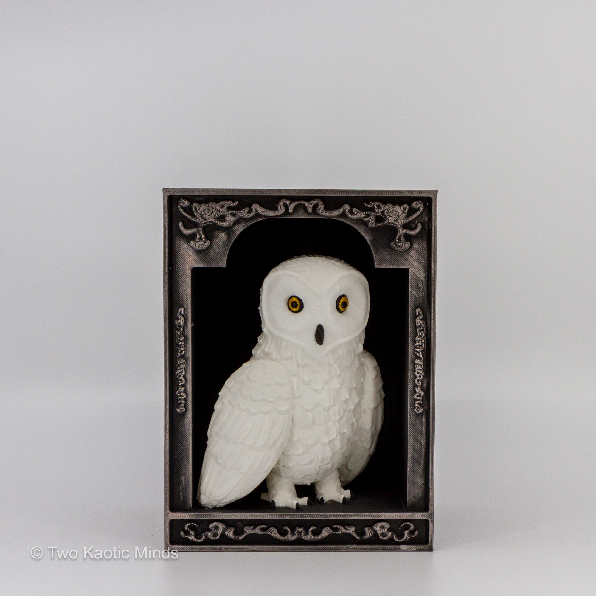 3D printed Harry Potter inspired owl book nook with white snowy owl inside a matte black ornately framed box with hand-applied pewter Rub and Buff filigree detail, front view