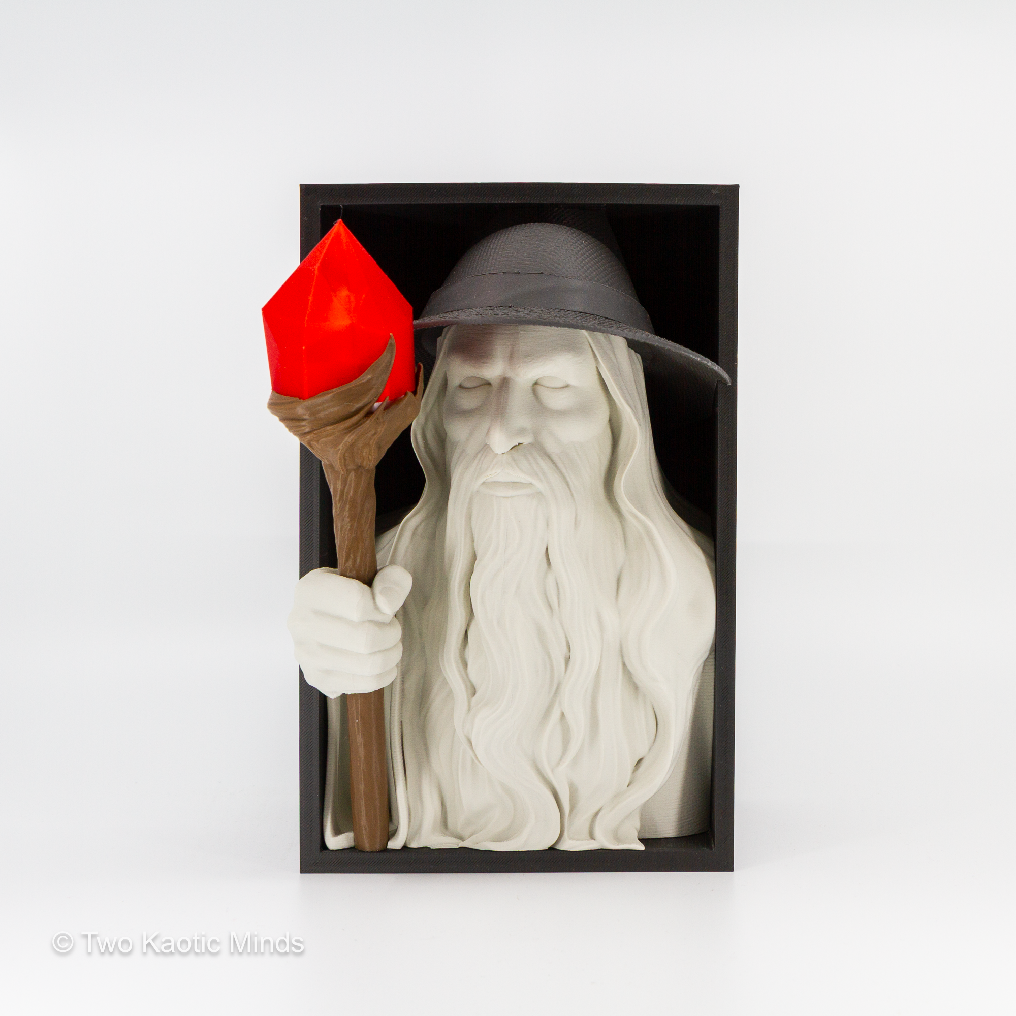 3D printed Lord of the Rings inspired wizard book nook showing a white bearded wizard in grey hat holding a brown staff with glowing red LED lantern, emerging from a matte black box, front view