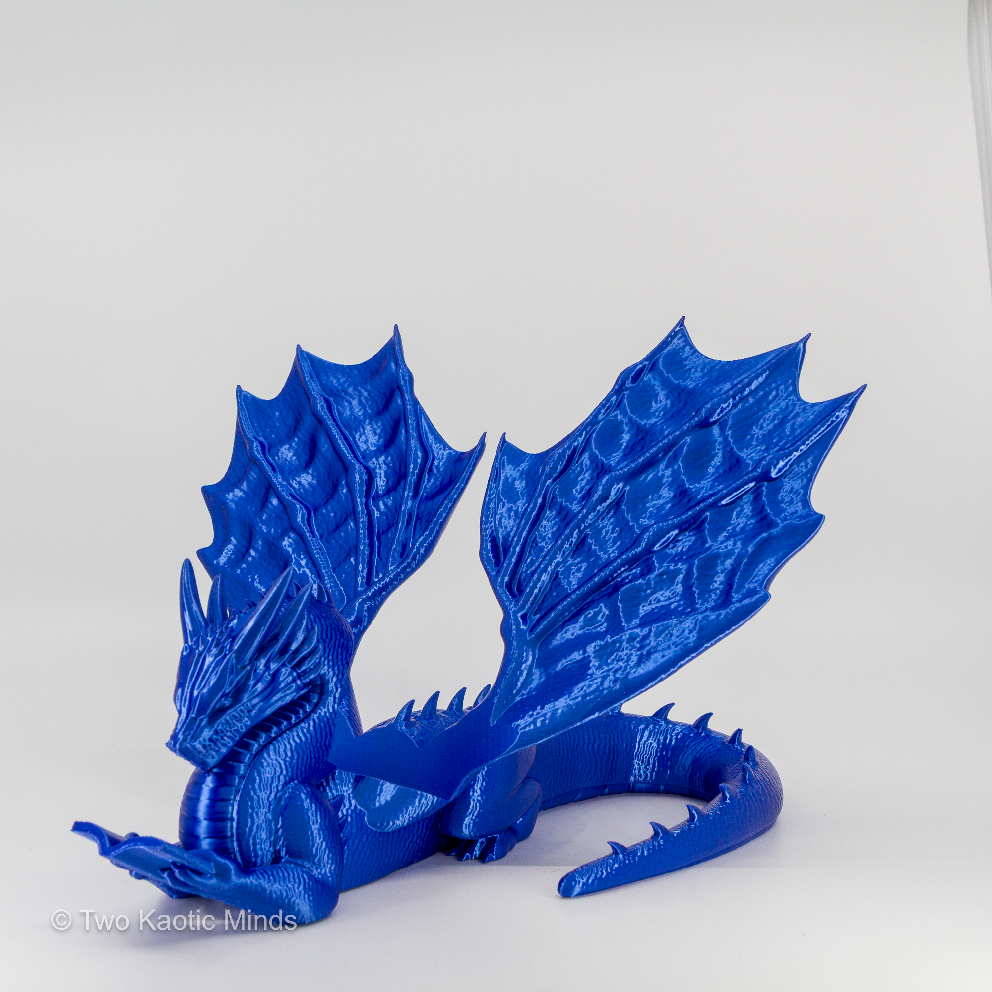 Rear angle view of blue 3D printed dragon book holder showing full wing span