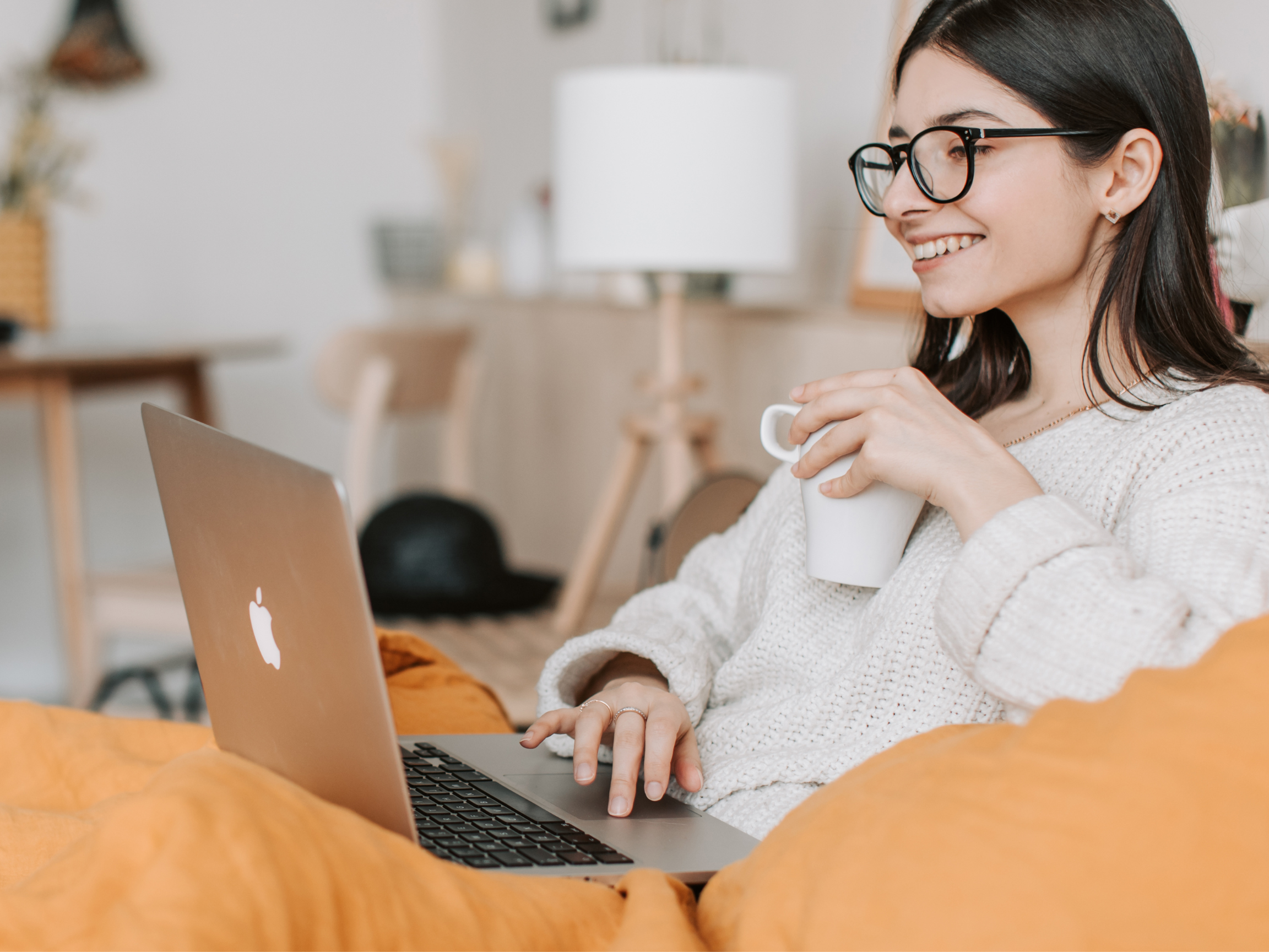 A woman sitting comfortably with her laptop, feeling calm and reflective during an online individual therapy session with Kristin Crumbley, LMHC, LMFT.