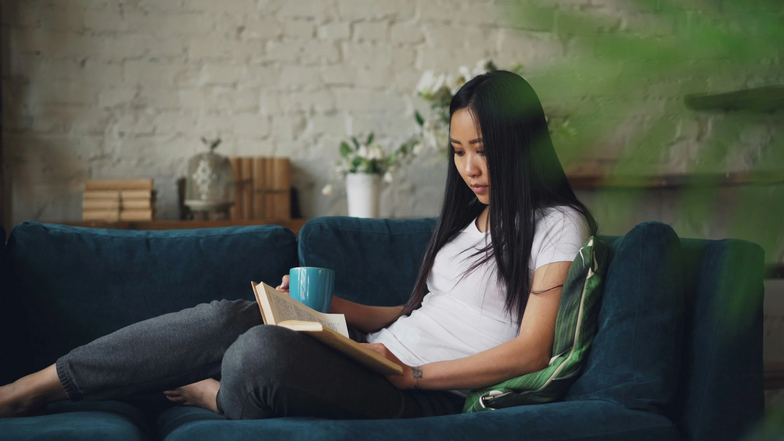 A woman sitting quietly at home with a book and mug, representing the internal world of relational anxiety that anxiety therapy in Florida helps address at Collected Connections