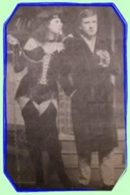A woman and a man in vintage attire standing side by side in a black and white photo.