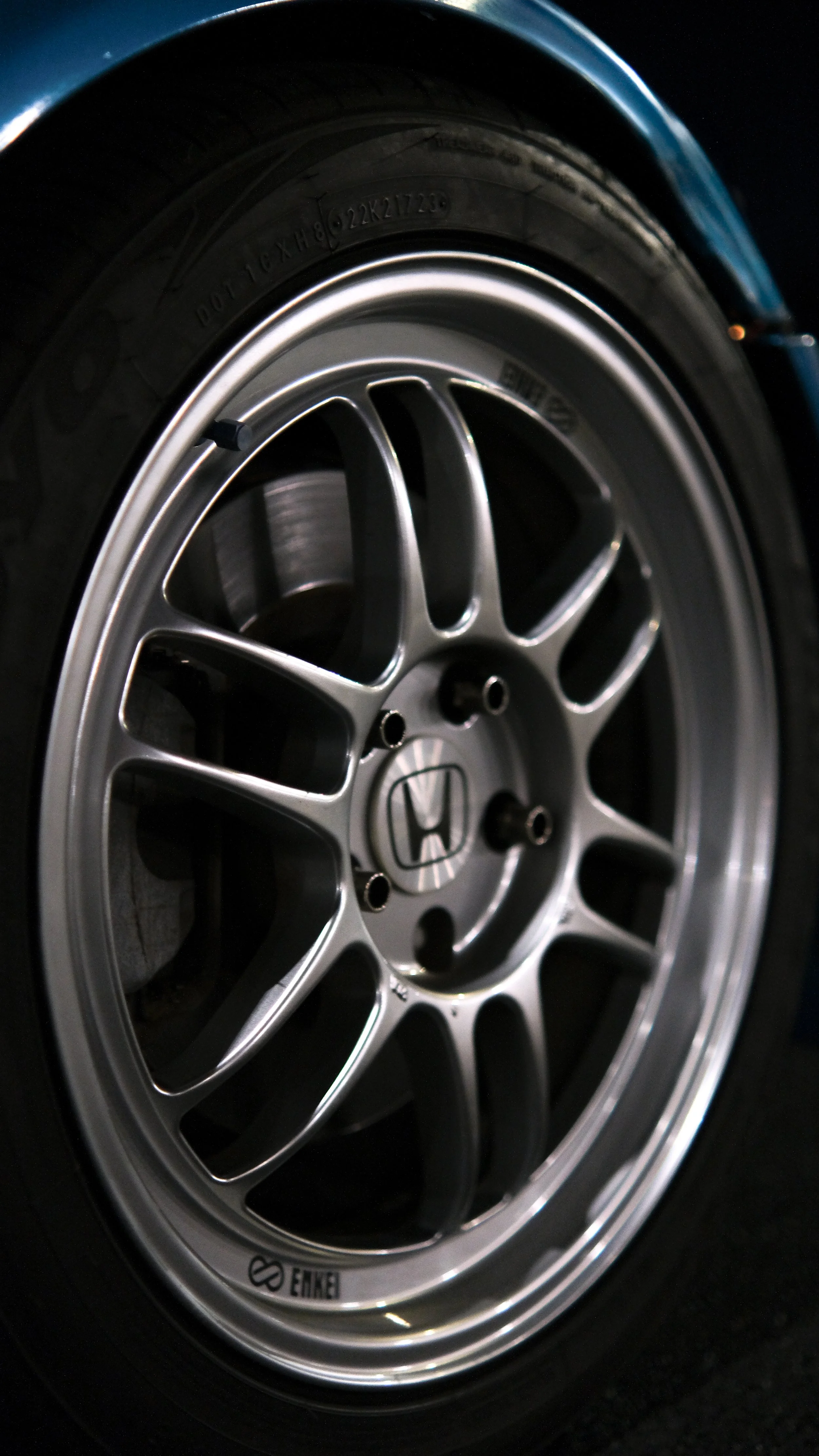 Close-up of a car wheel with a silver alloy rim and a black tire.