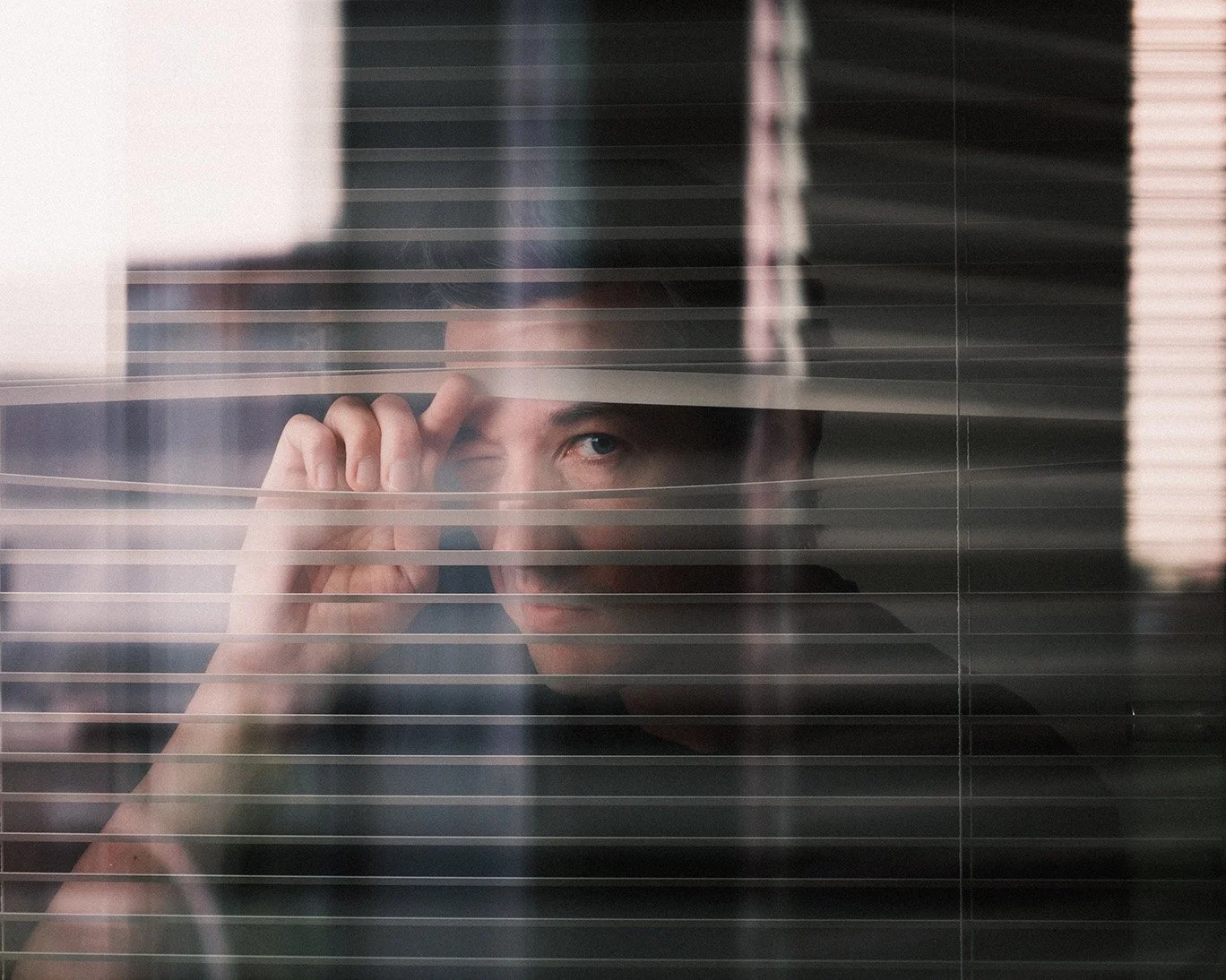 person peeking through window blinds