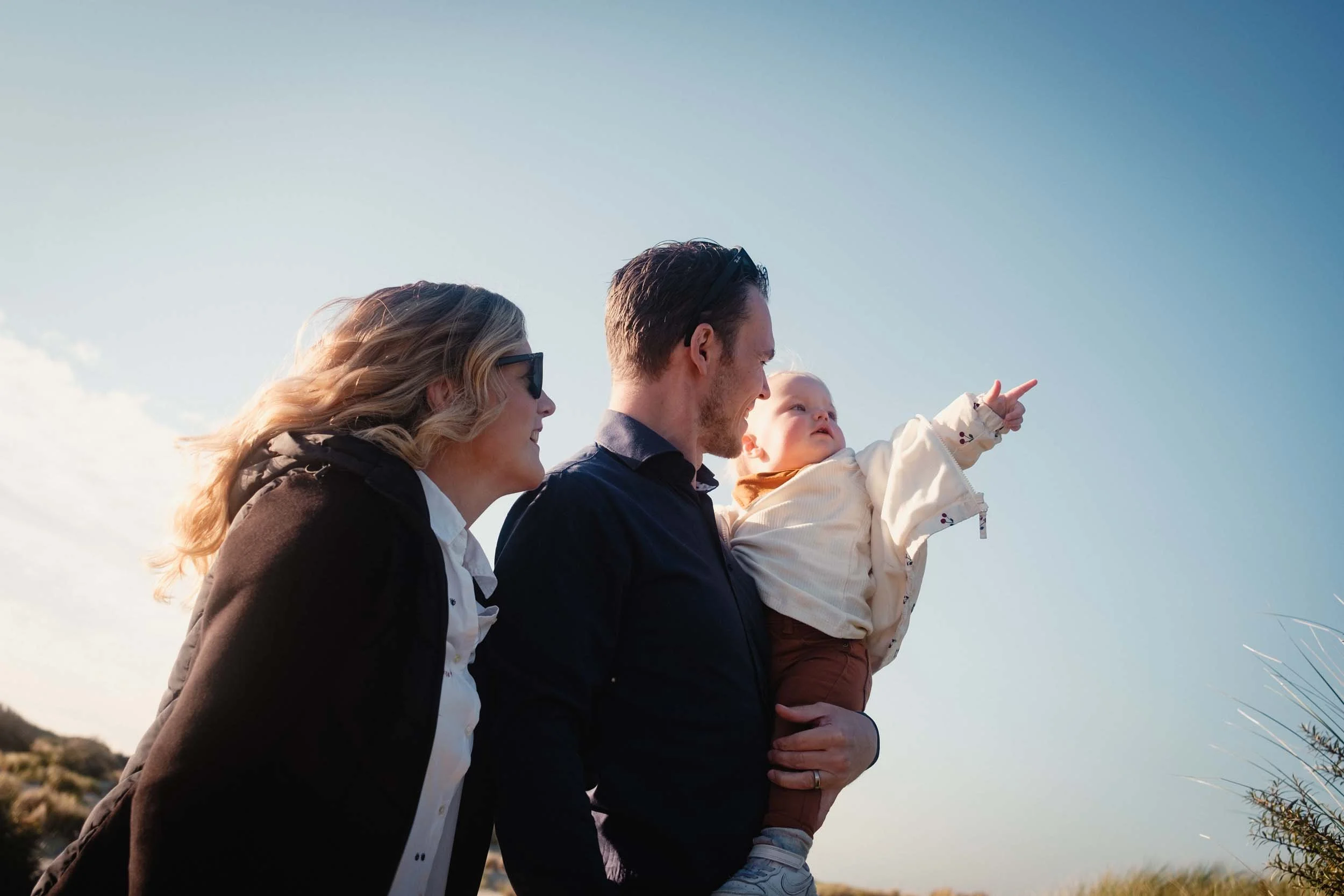 young girl points into distance while being held by father