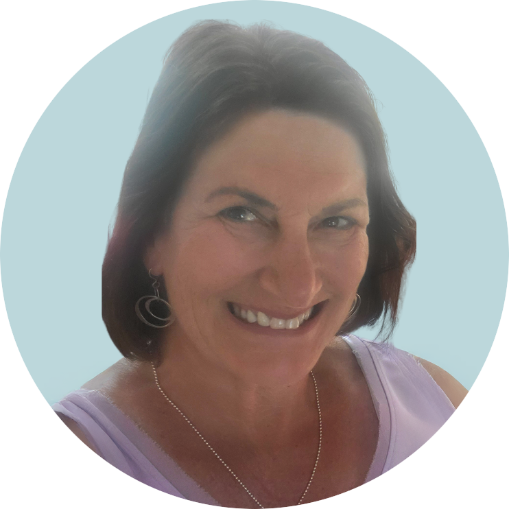 A smiling woman with short brown hair wearing earrings, a necklace, and a sleeveless top with a light purple color.
