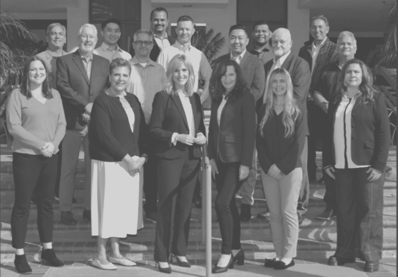 NUVIS team posing for a photo in an office setting, standing in several rows, dressed in business attire.