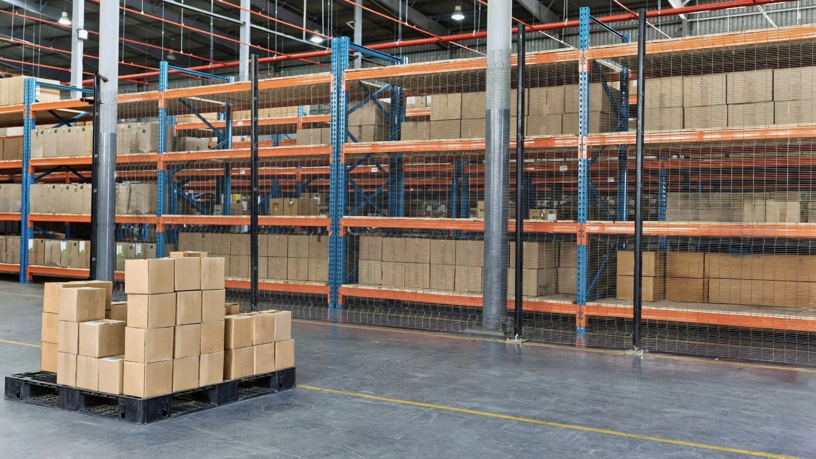 Pallet of imported goods beside a secure caged storage area in a UK bonded warehouse, with marked floor lanes