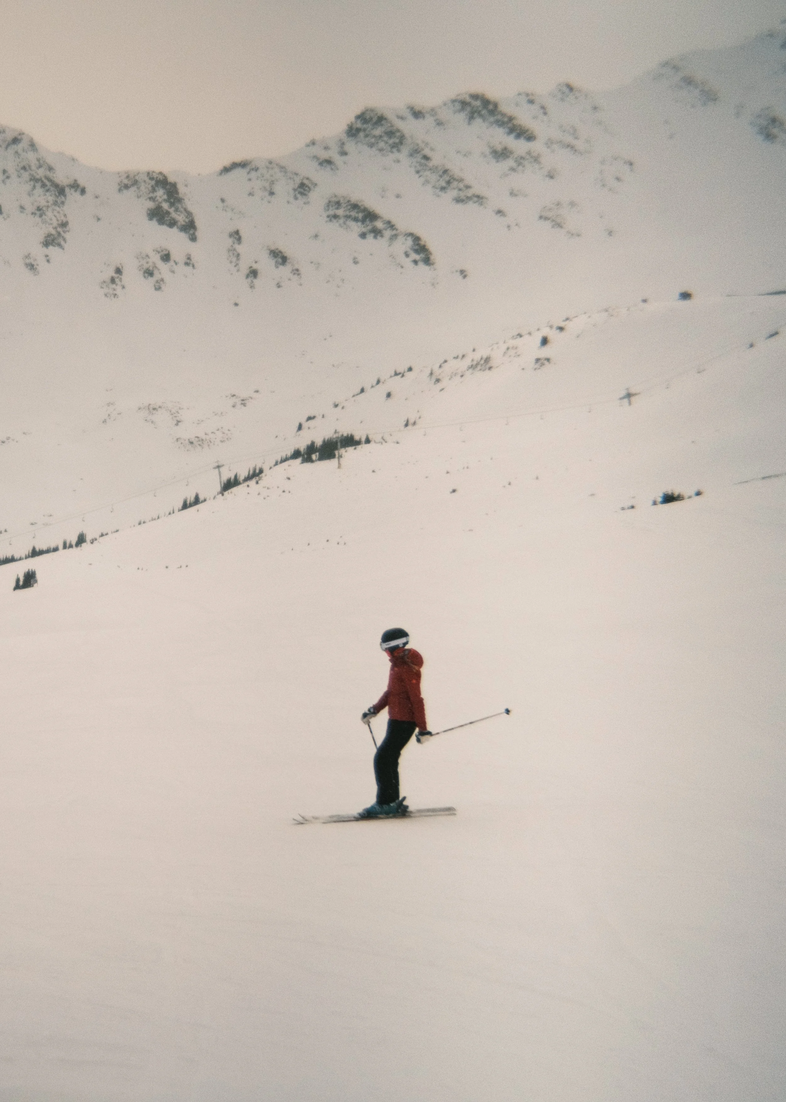 A person skiing on a snowy mountain slope with snow-covered mountains in the background.