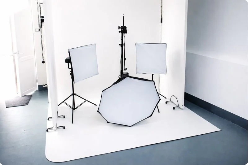 Photography studio setup with lighting equipment and a white backdrop.