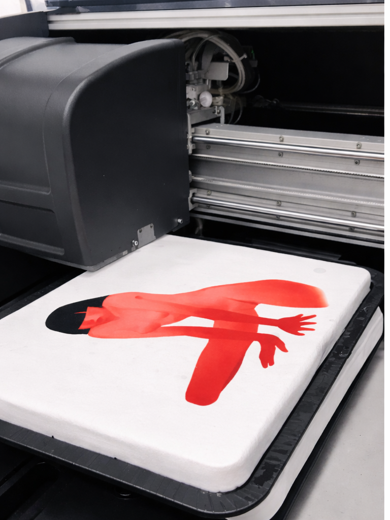 A large DTG printer is printing a red and black image of a reclining woman on a white fabric or material.
