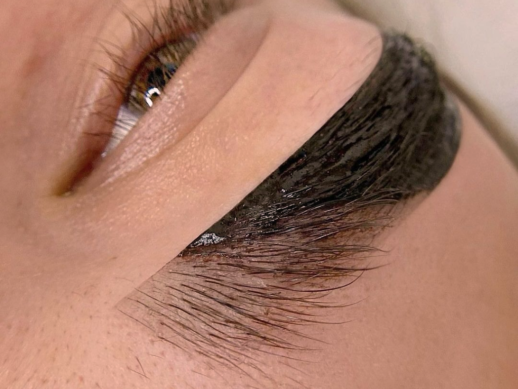Close-up of a person's eye with eyelash extensions and eye makeup, featuring eyeliner and eyeshadow.