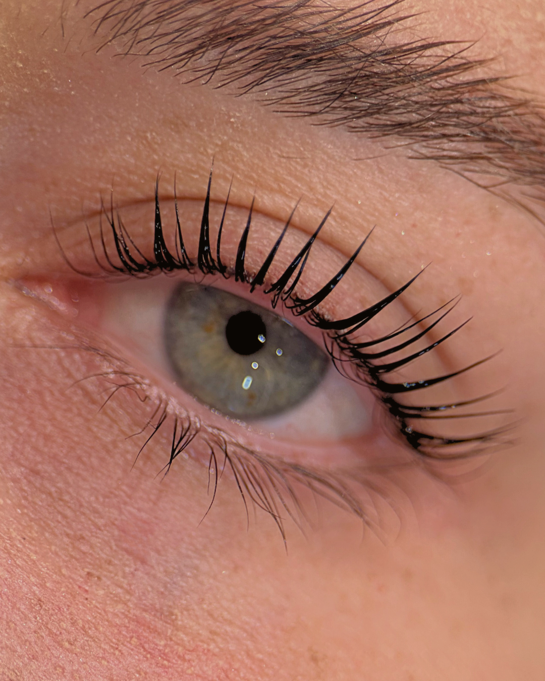 Close-up of a human eye showing the iris, pupil, eyelashes, and surrounding skin.