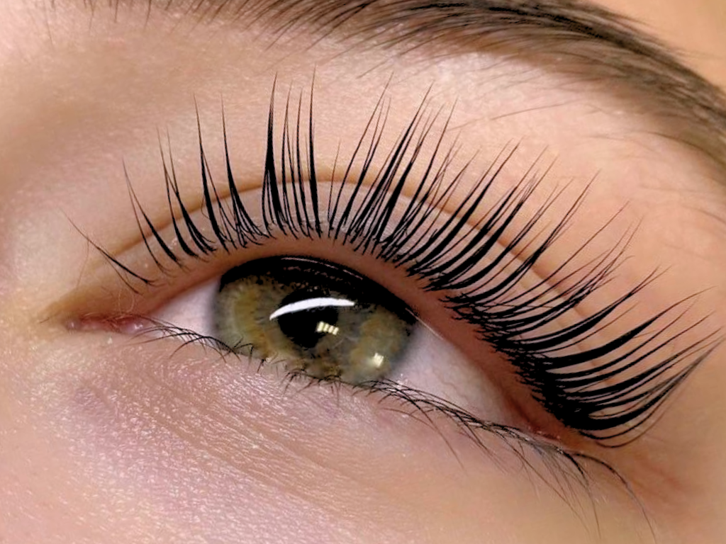 Close-up of a person's eye with long, dark eyelashes and greenish-brown iris.