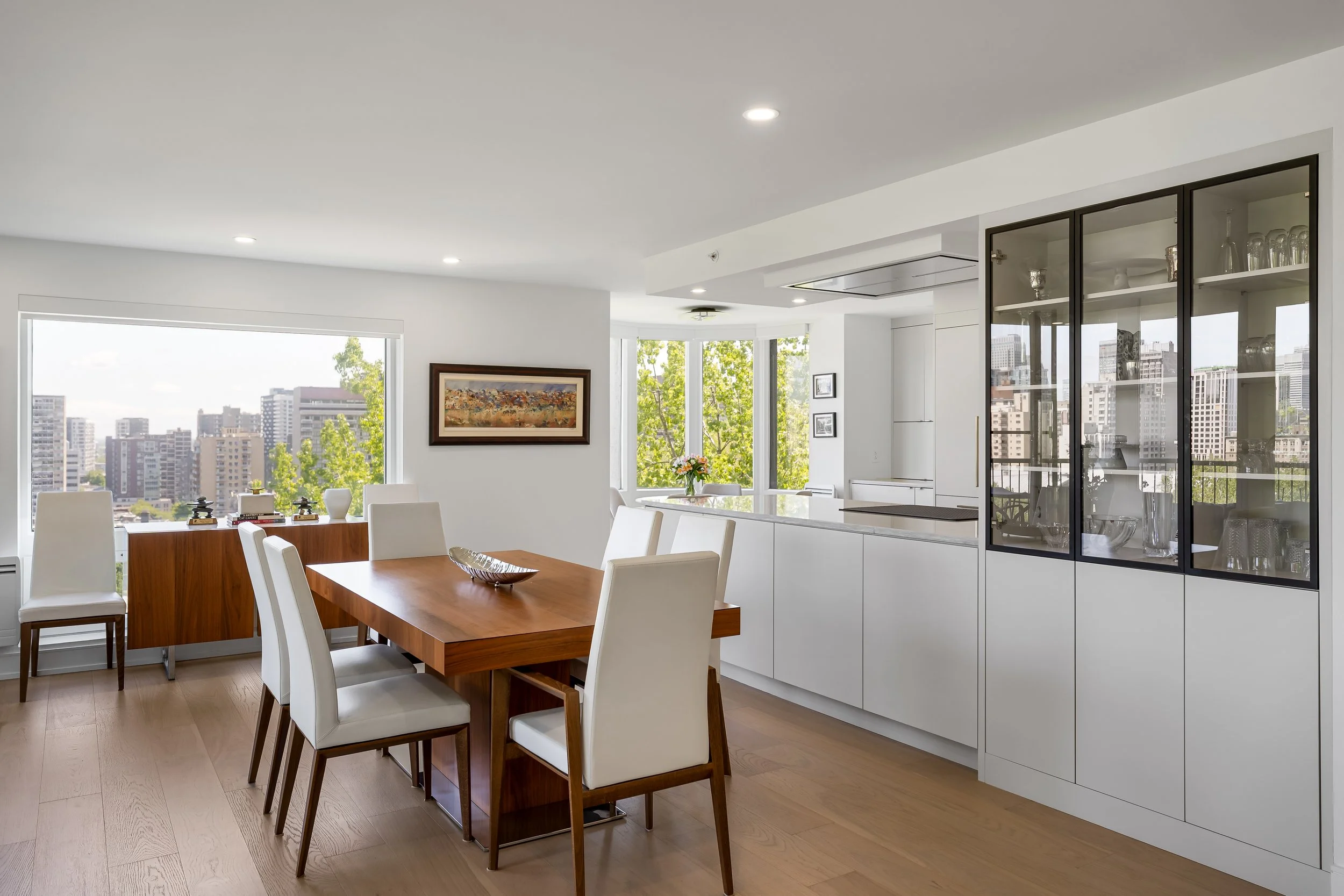 Residential luxury condo renovation in Montreal featuring an open dining area with custom cabinetry and large windows.