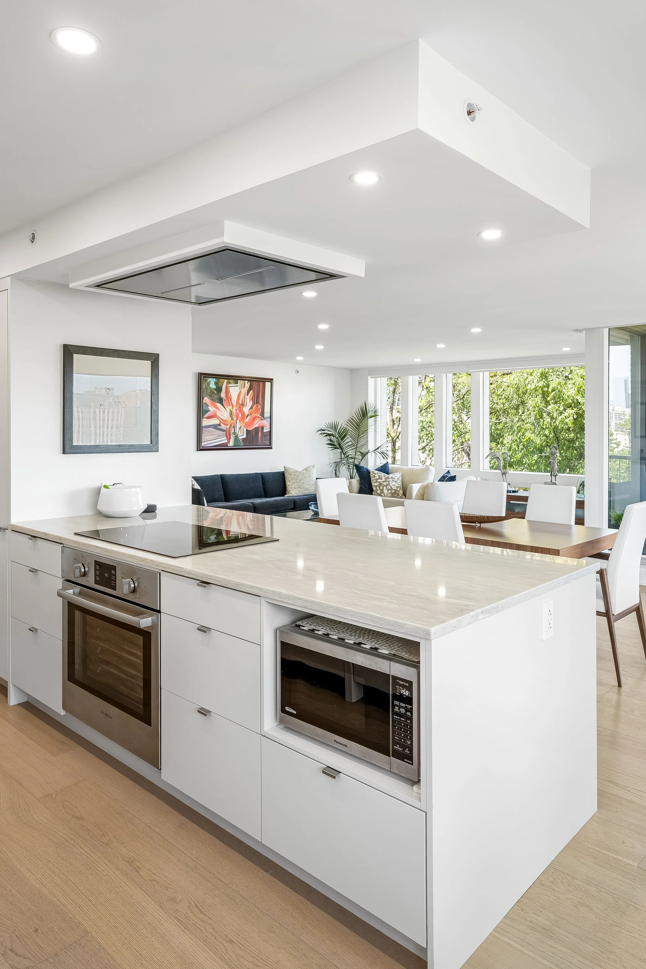 High-end residential condo renovation in Montreal with large peninsula with built-in oven and cooktop, quartz countertops and integrated ceiling fan. 