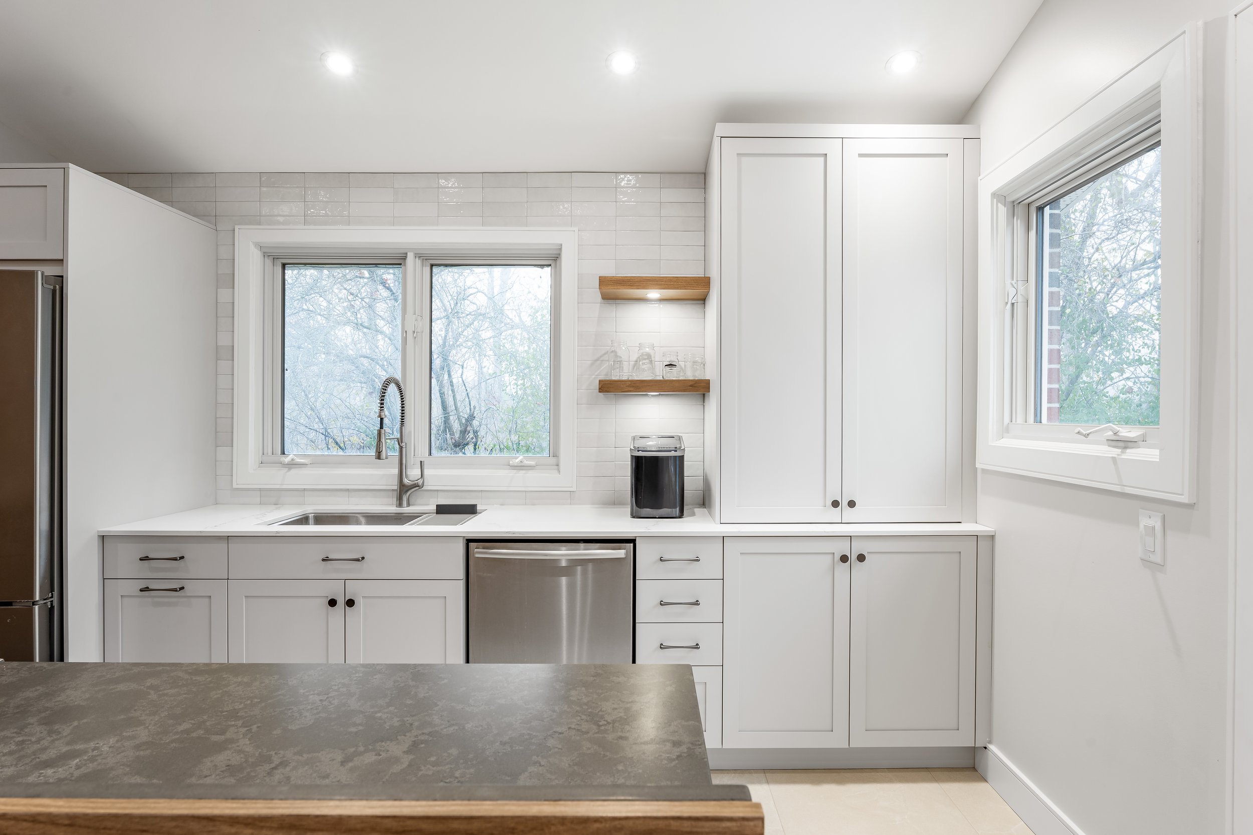 Custom kitchen renovation in Pointe-Claire Montreal with open shelving, integrated lights and white shaker custom cabinets. 