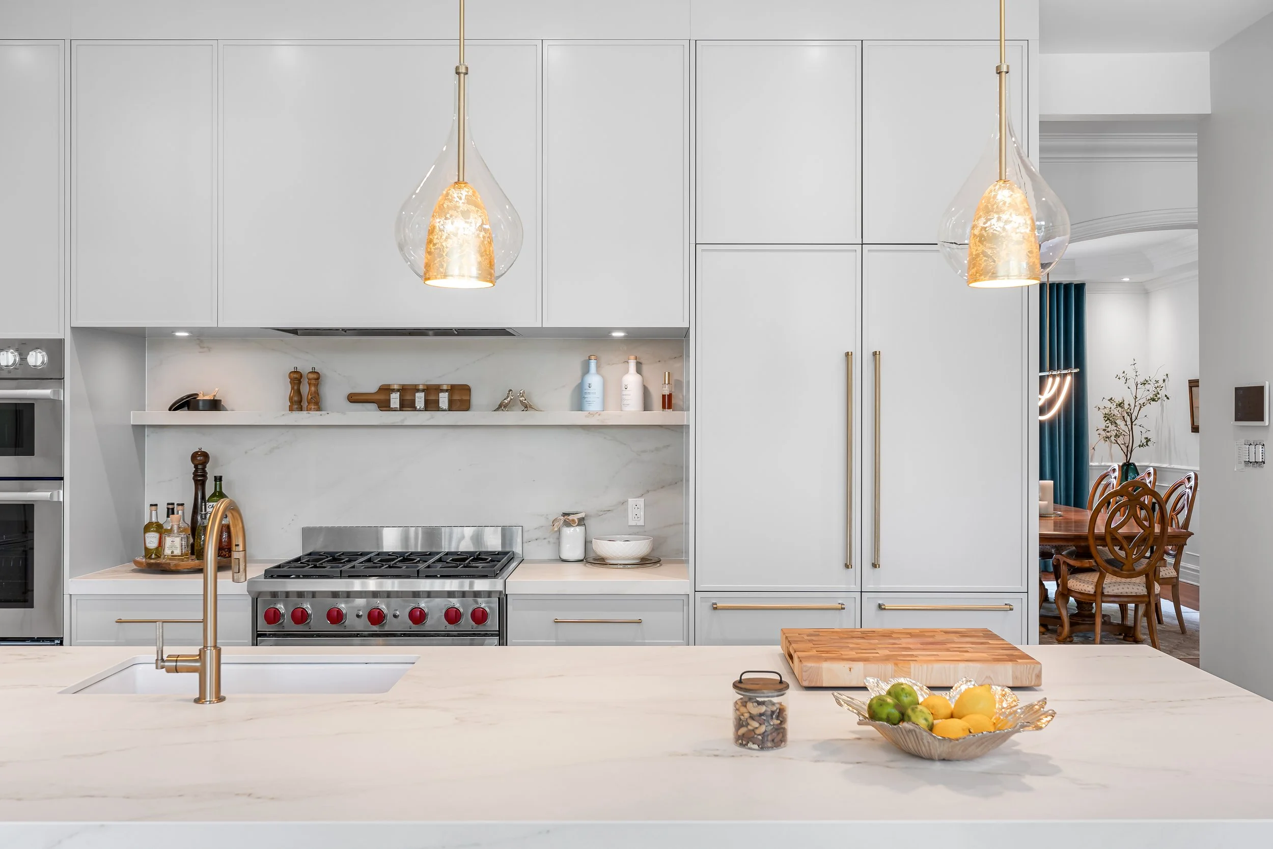 Luxury custom kitchen renovation in Brossard near Montreal featuring light colored cabinets, an integrated fridge, and light Dekton countertops. 