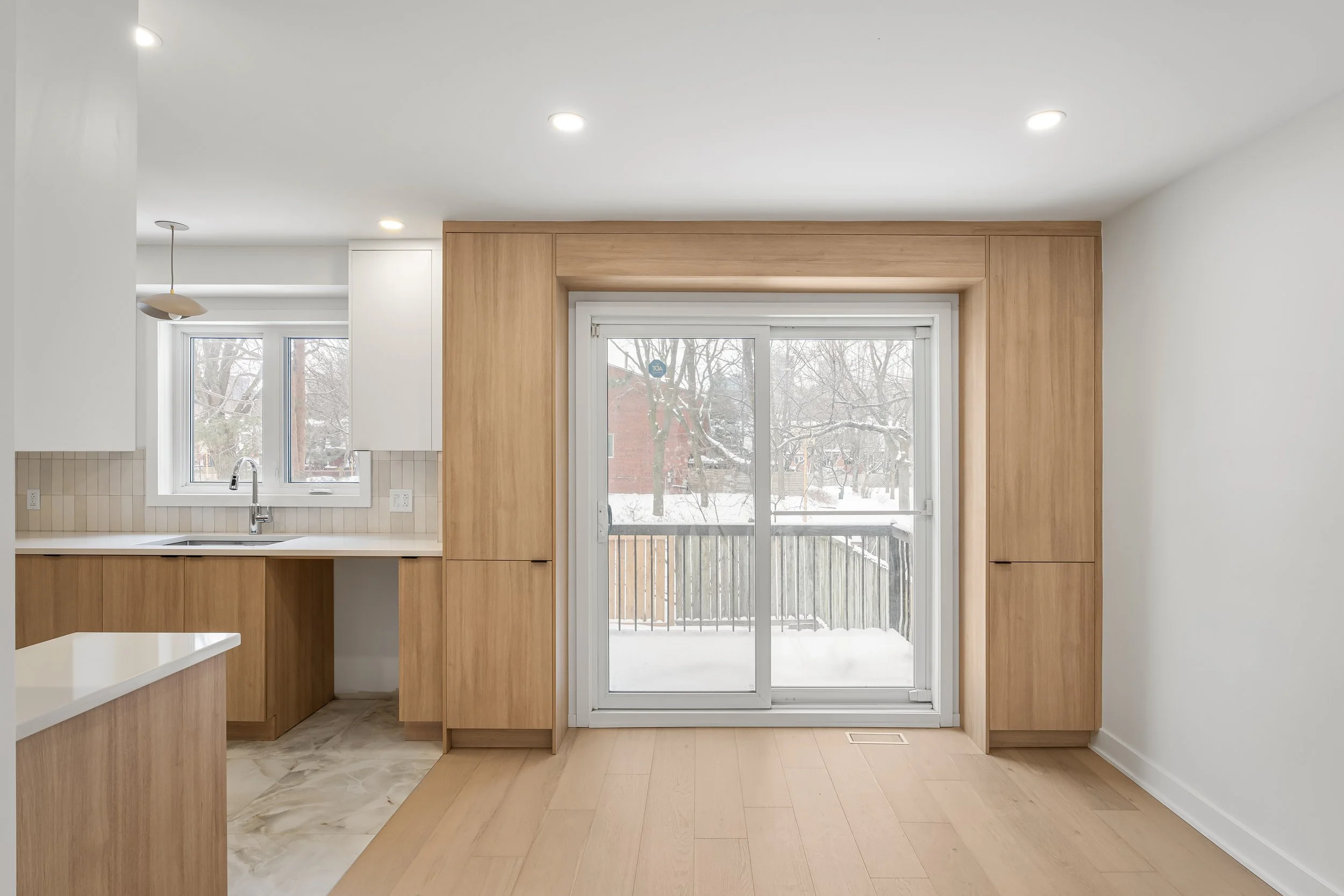 Residential first floor renovation in Montreal featuring custom built-in cabinets around the patio door in flat oak panels. 